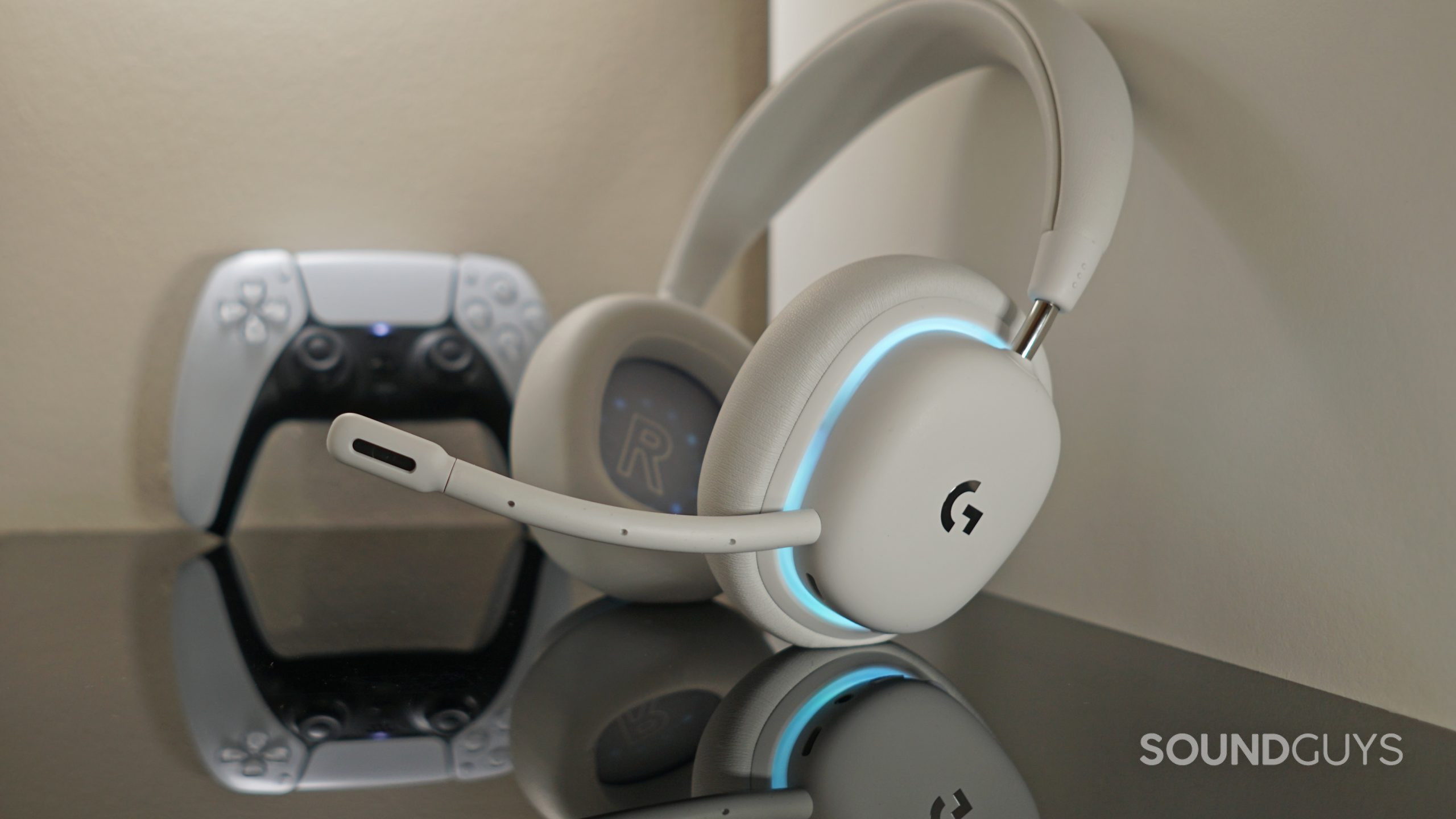 The Logitech G735 sits on a white shelf in front of a Sony DualSense controller.