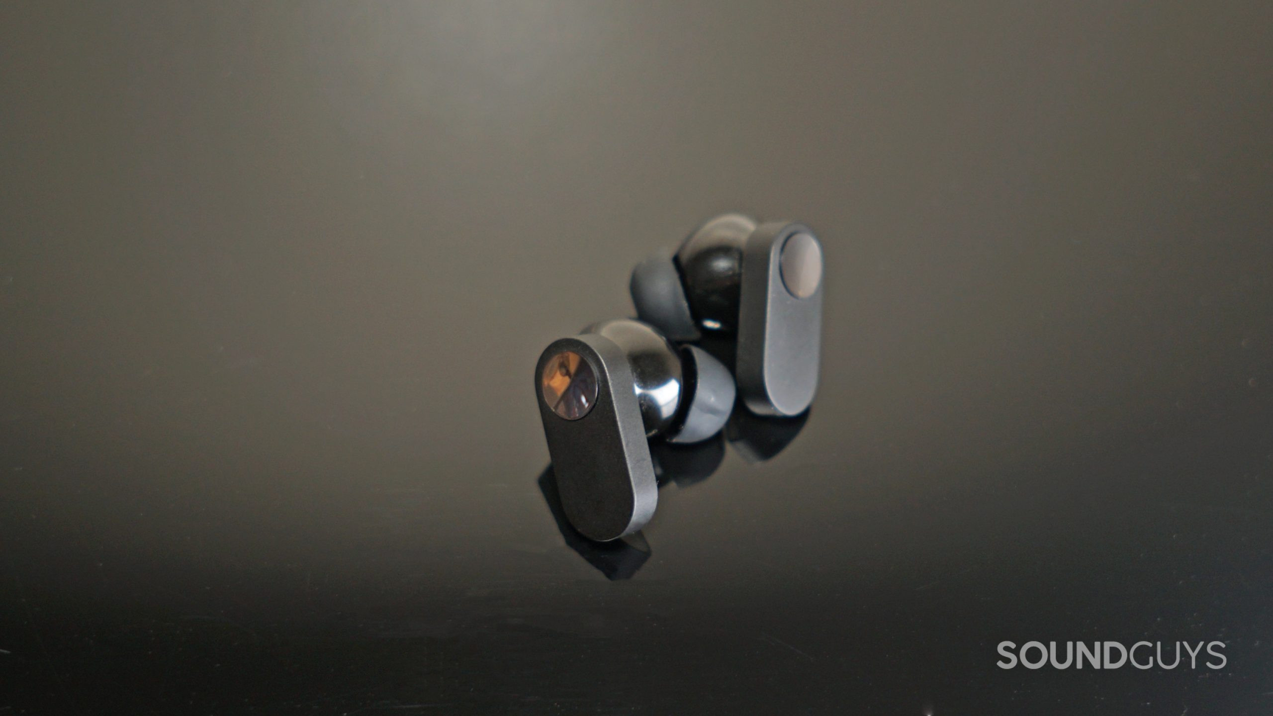 The OnePlus Nord Buds lay on a black lacquer surface.