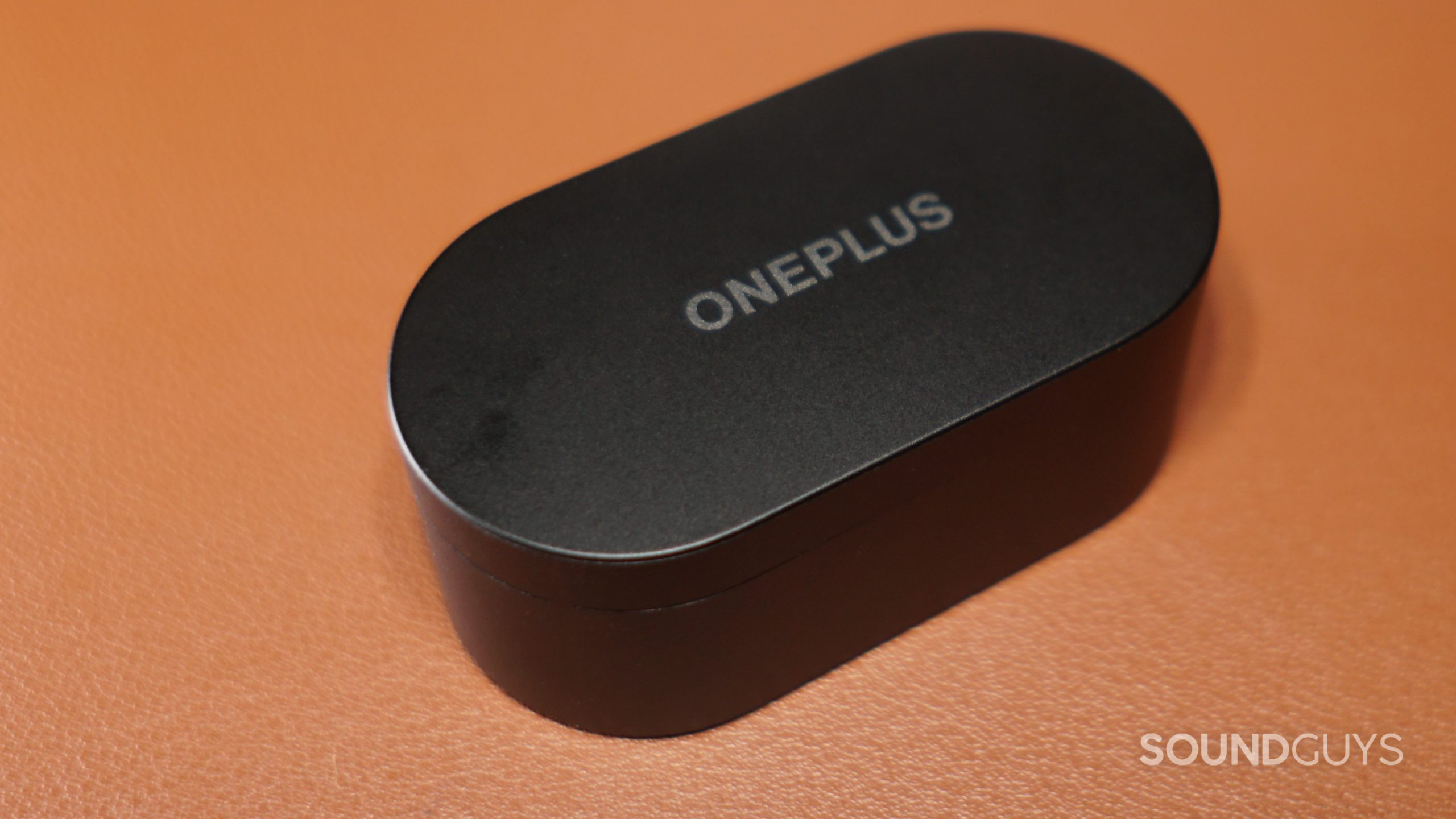 OnePlus-Nord-Buds-case The OnePlus Nord Buds charging case sits closed on a leather surface.