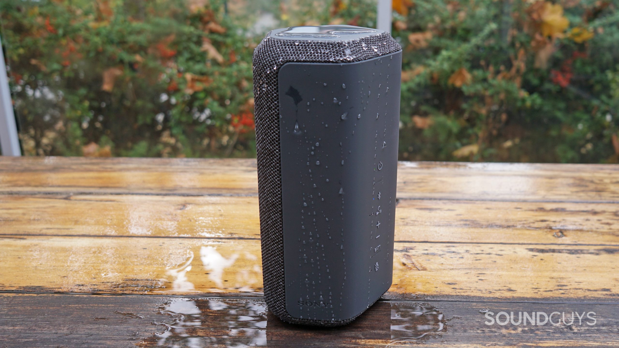 The Sony SRS-XE300 sits on a wooden table after being splashed with water.