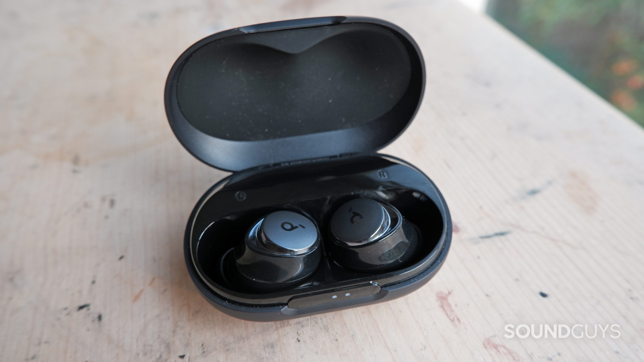 The Anker Soundcore Space A40 inside its case on a wooden table.