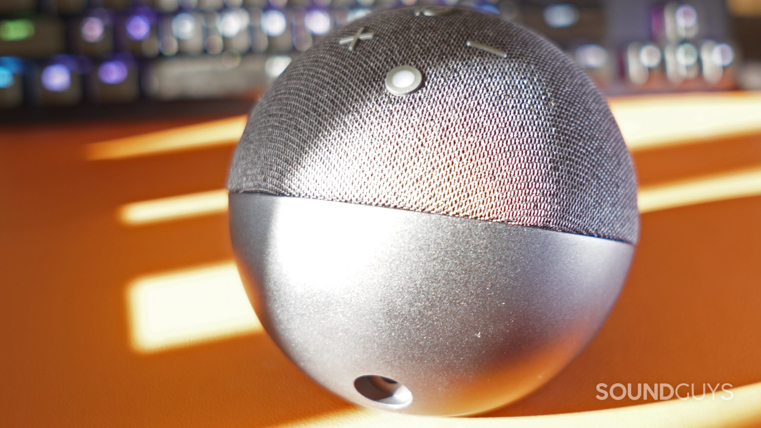 Amazon-Echo-Dot-(5th-gen)-port The Amazon Echo Dot (5th Gen) sits on a leather surface with its power port in view, and a HyperX mechanical gaming keyboard in the background.