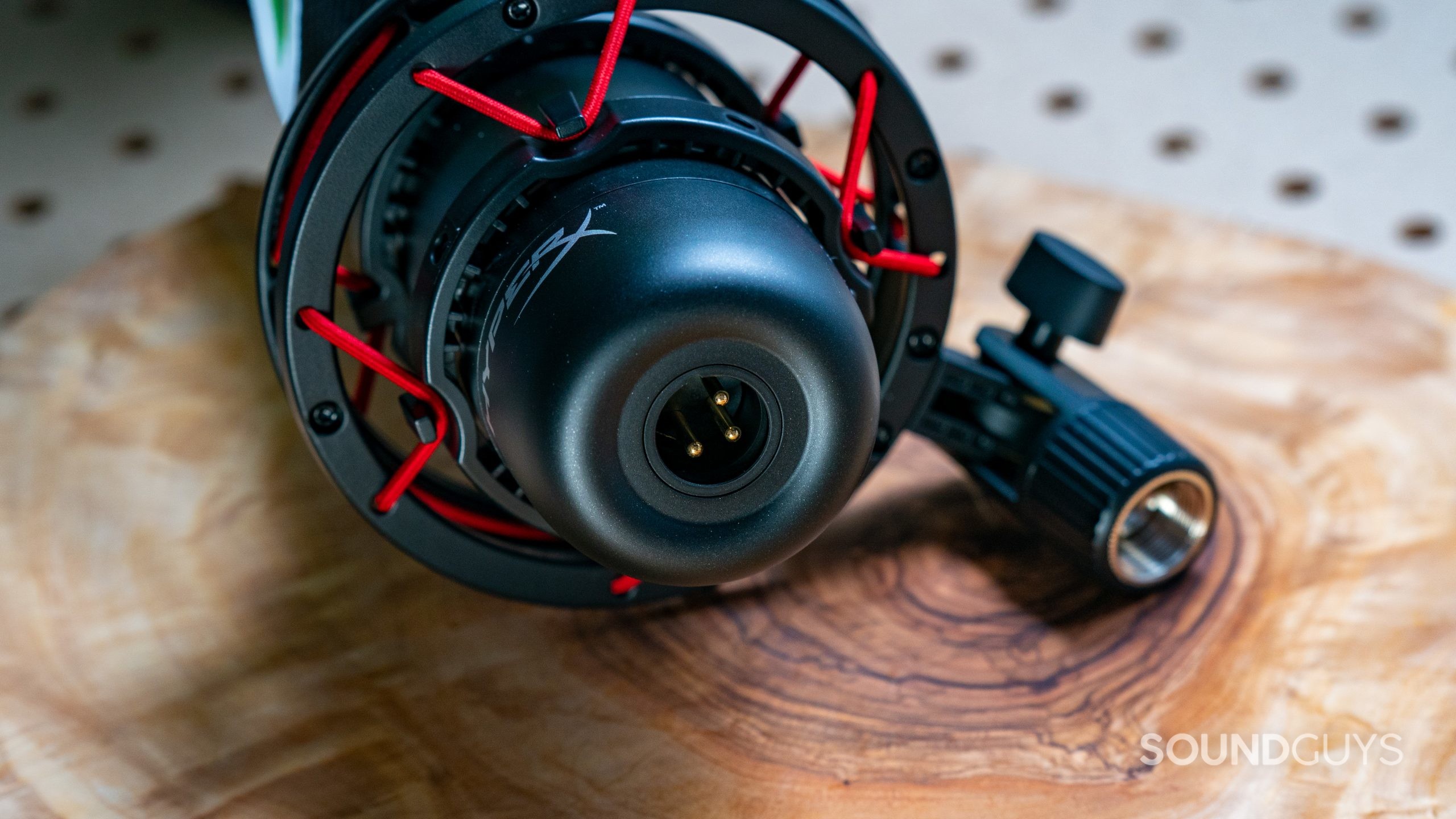The HyperX ProCast sits on a wooden service, with its XLR port in view.