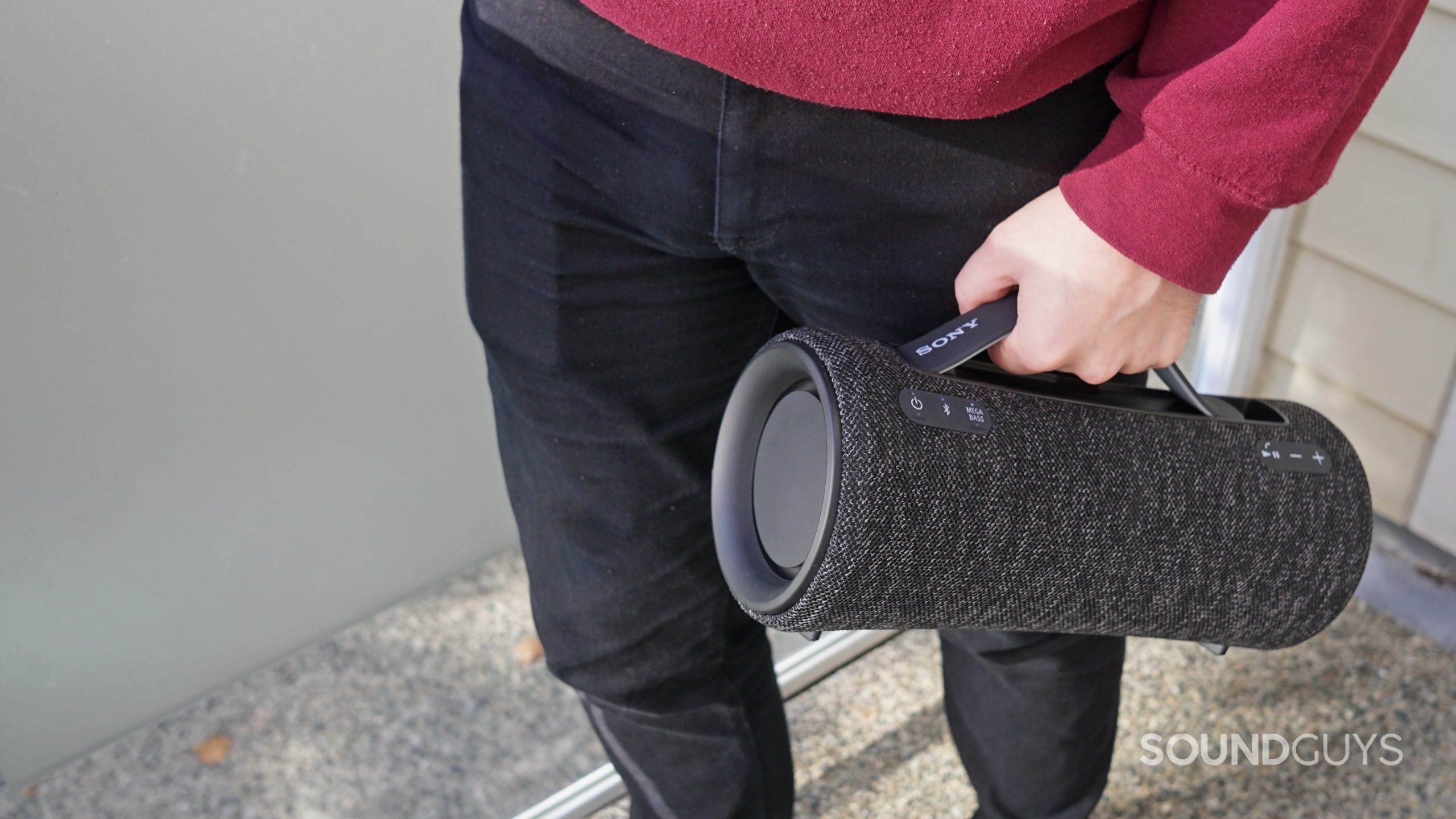 A man stands holding the Sony SRS-XG300 by its handleoutside.