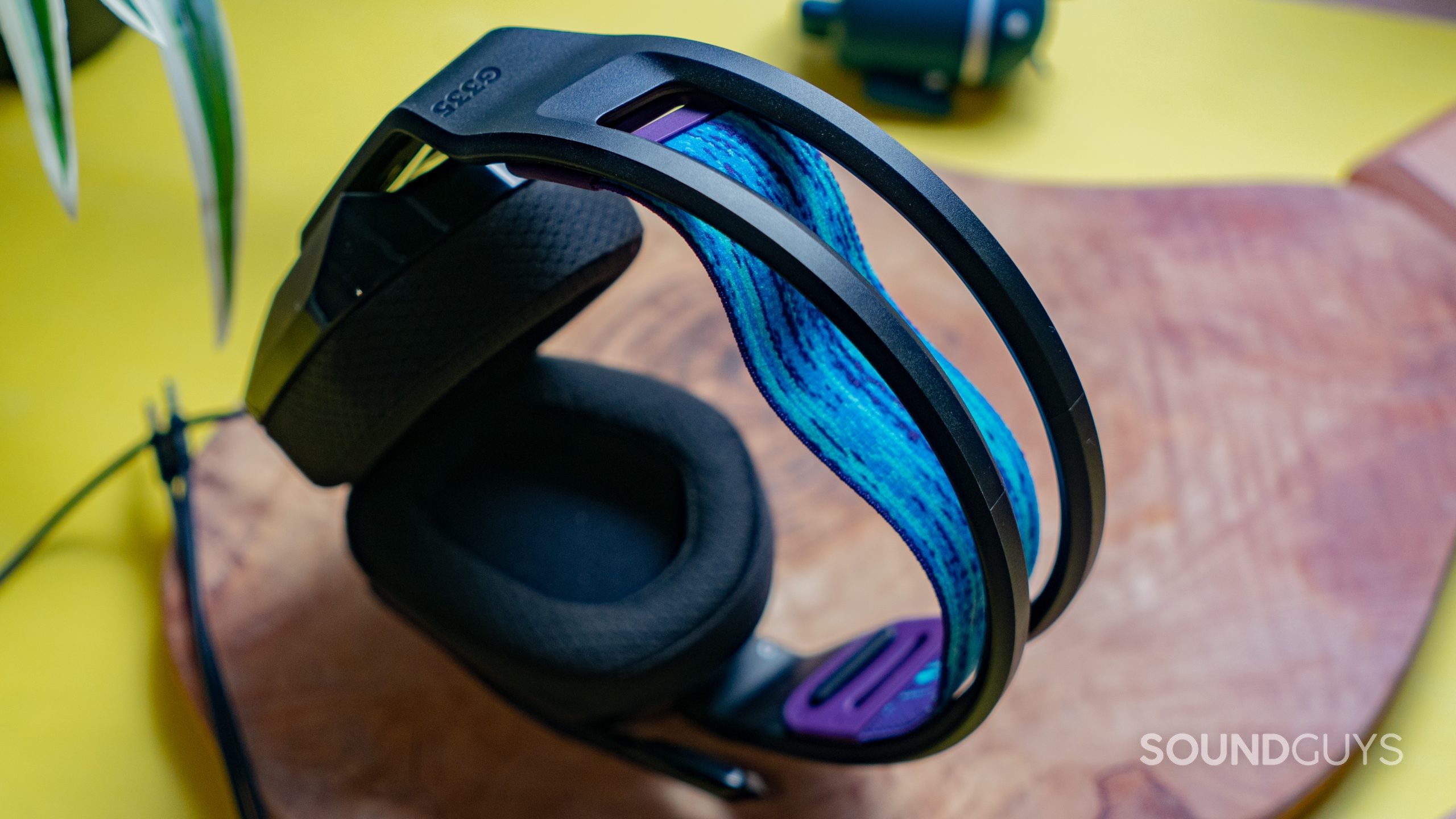 The Logitech G335 blue and purple stretchy headband on top of a wooden table.
