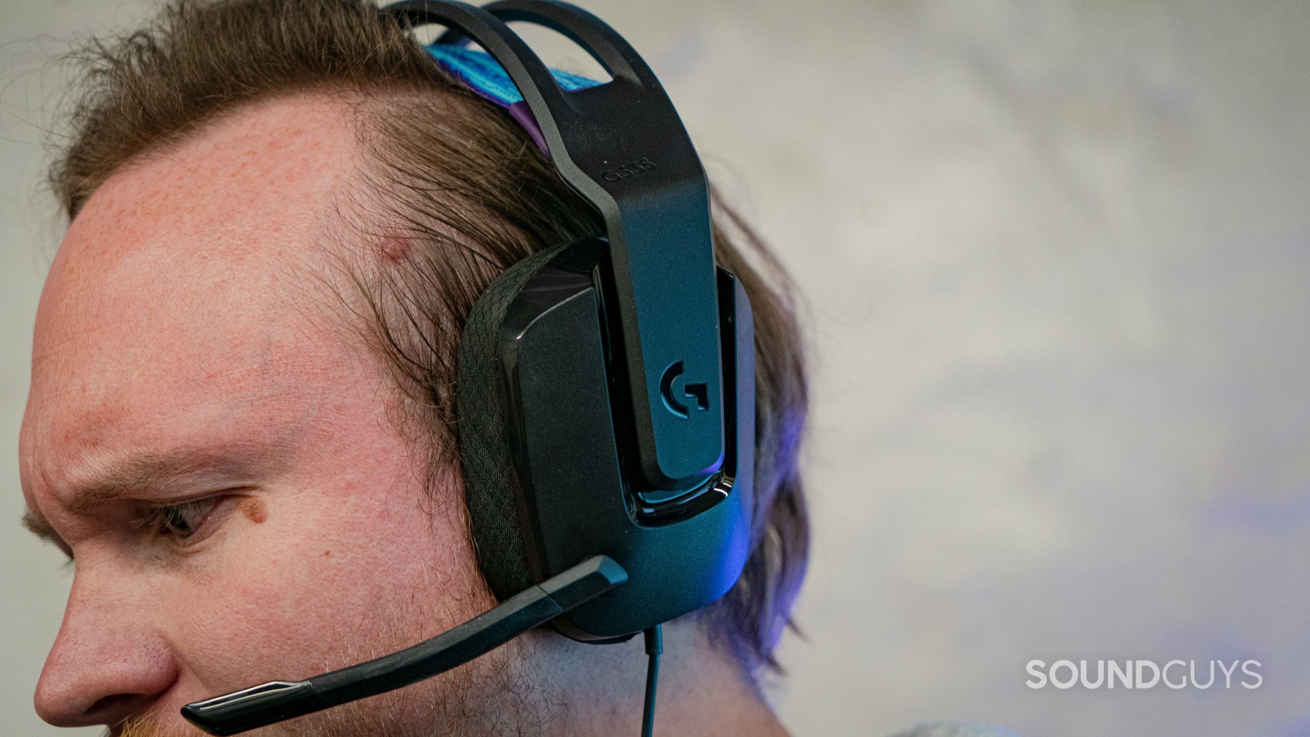 The Logitech G335 being worn on a man's head with the microphone extended down.