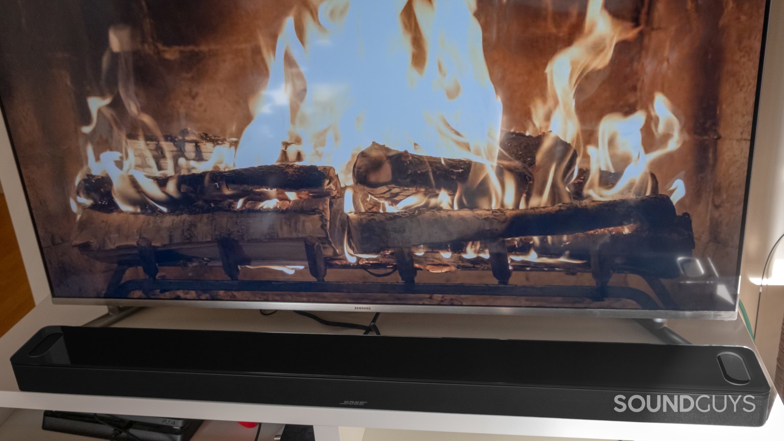 Image of a TV with a fireplace on screenthe Bose Smart Soundbar 900 in front.