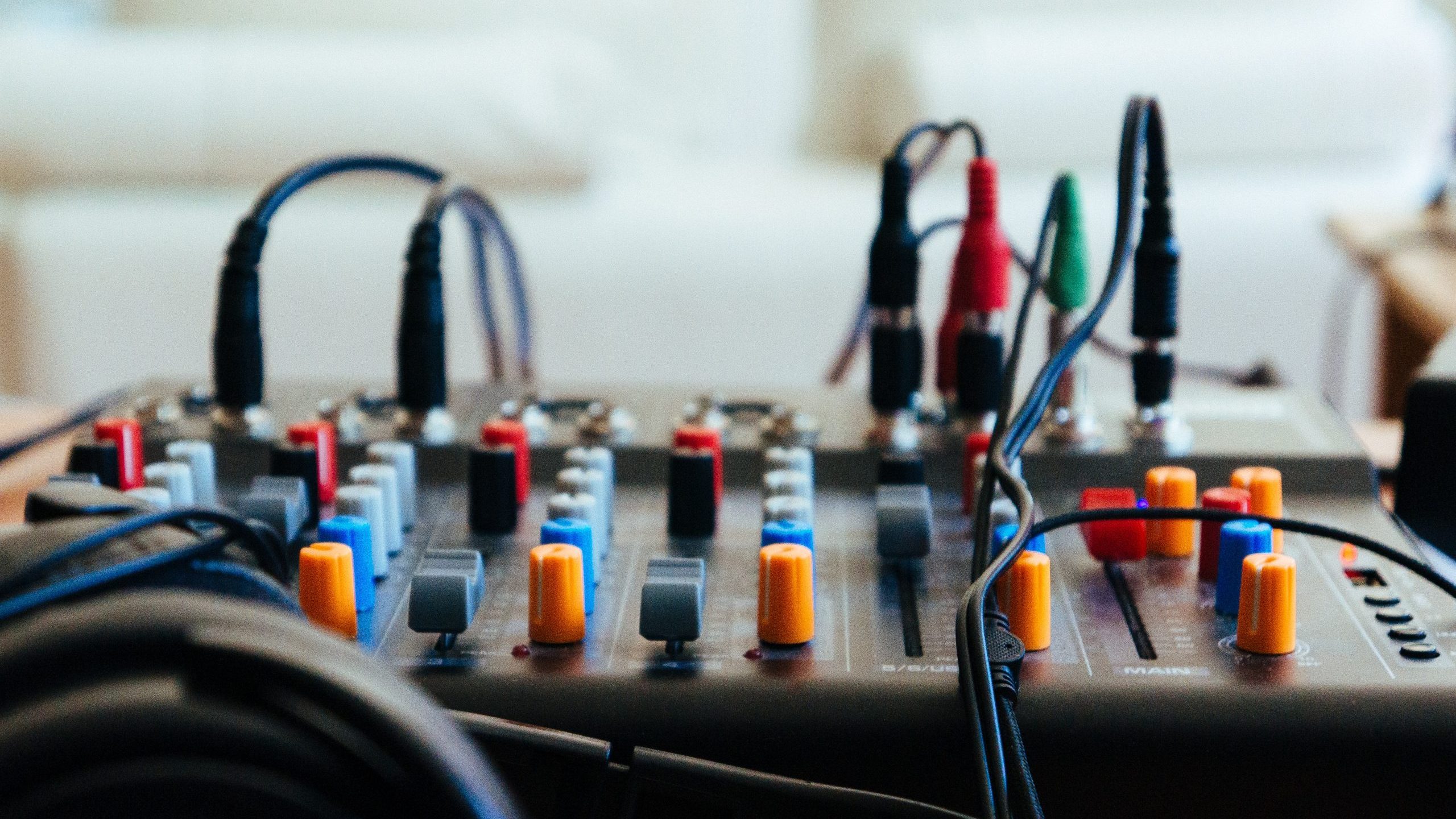 An audio mixer with an assortment of connected wires and adaptors.