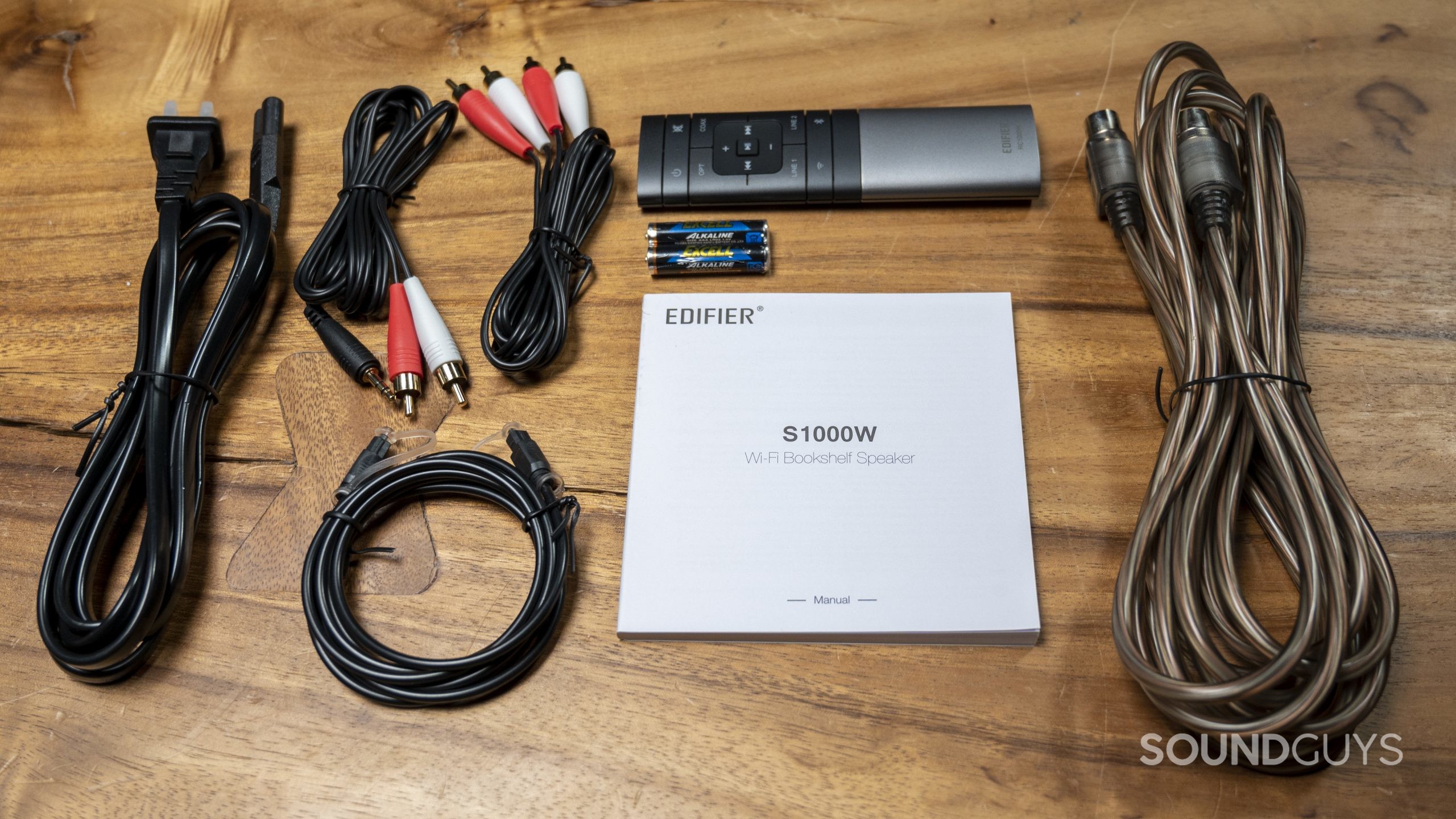 A top down image of the various included cables, remote, and manual for the Edifier S1000W.