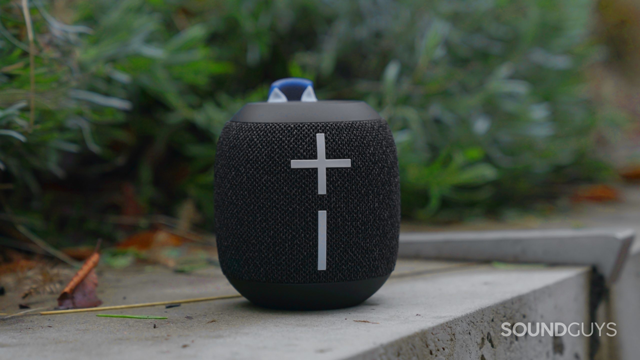 The Ultimate Ears Wonderboom 3 sitting on concrete with the volume controls in clear view.