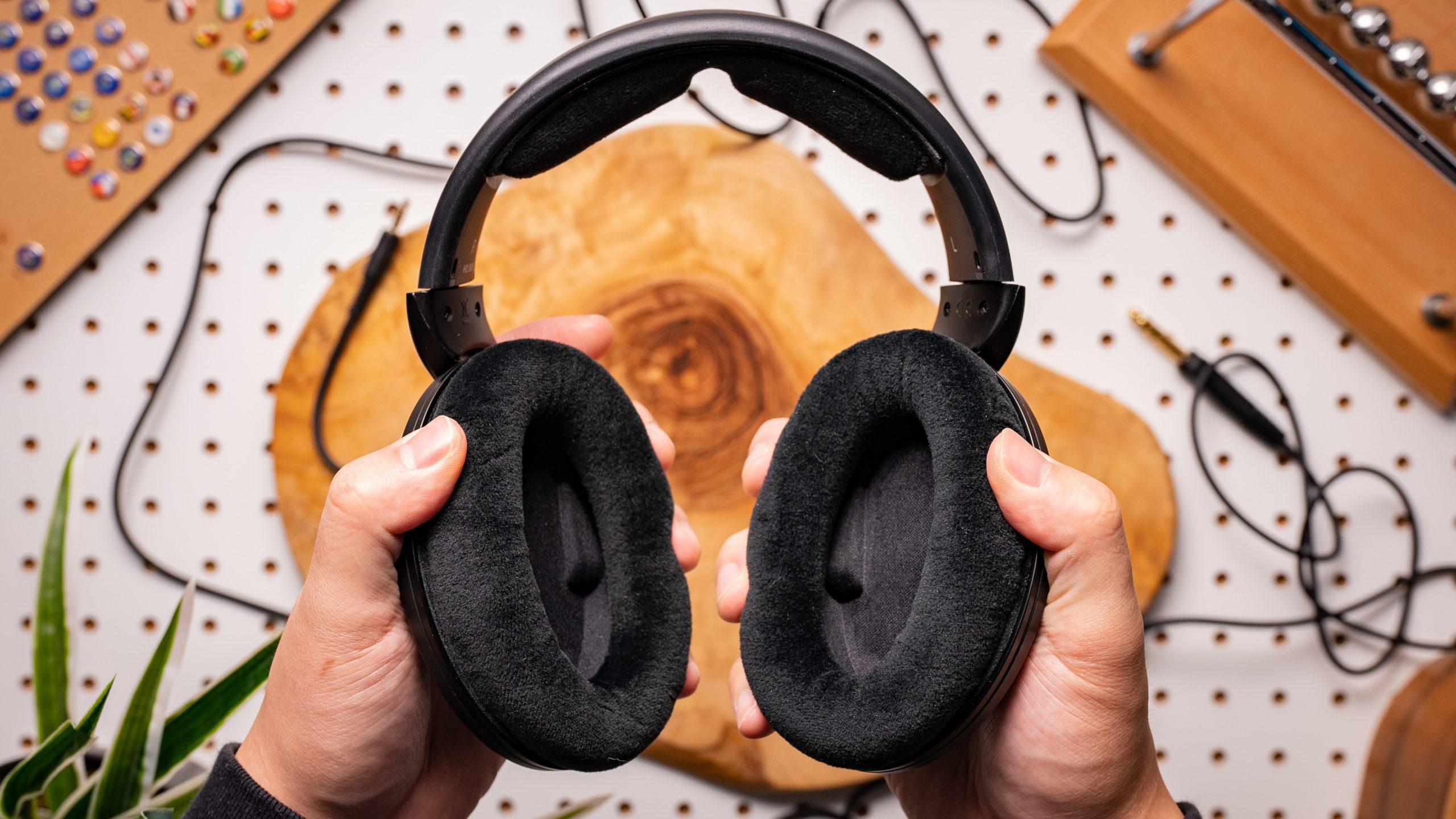 A photo of the Sennheiser HD 560S' cloth ear pads, held in front of wood and pegboard.