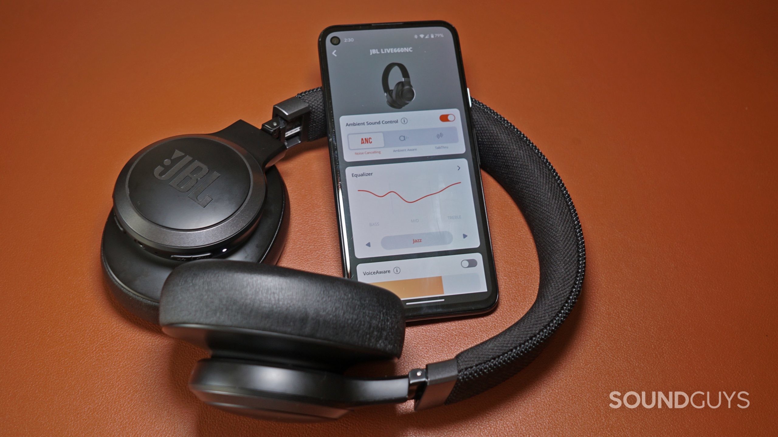 The JBL 660NC lays on a leather surface next to a Pixel 4a running the JBL Headphones app