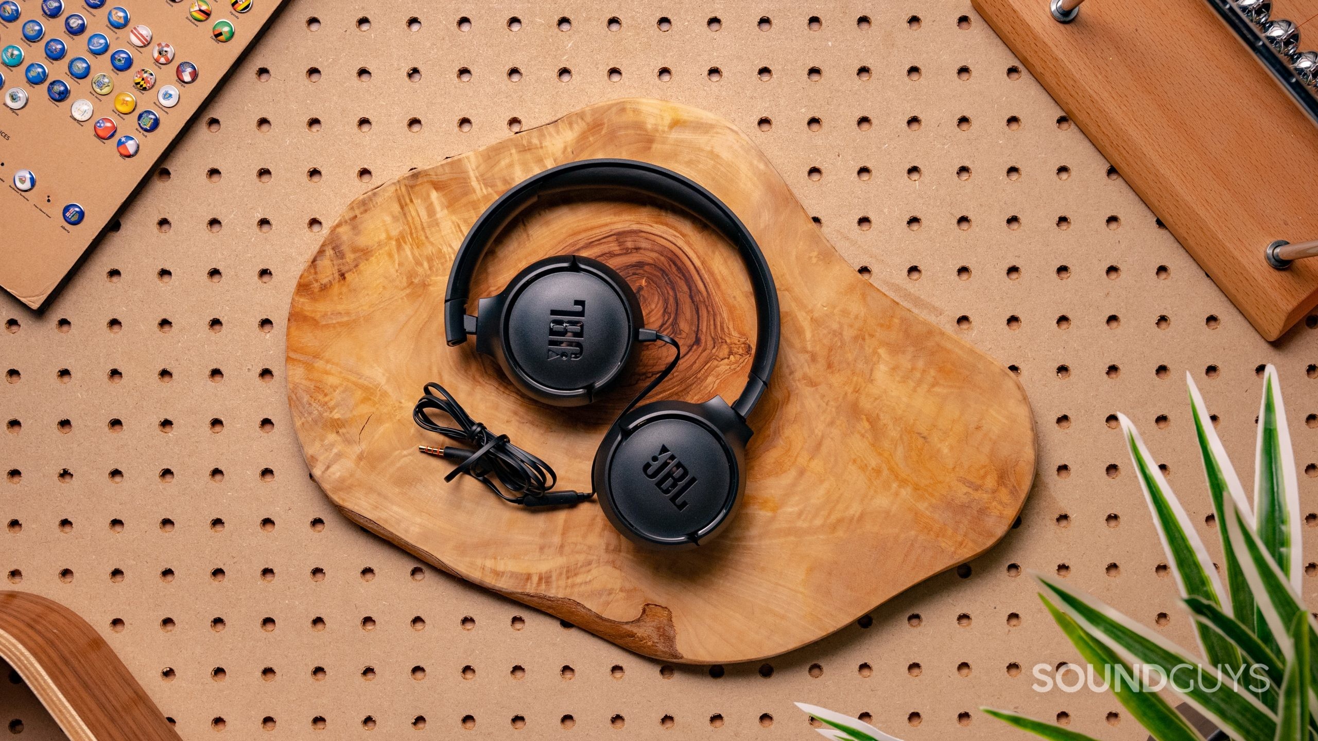 The JBL Tune 500 sitting neatly folded on a table with its headphone cable bundled up nicely, with the JBL logo displayed on the outside casing of the ear cups.