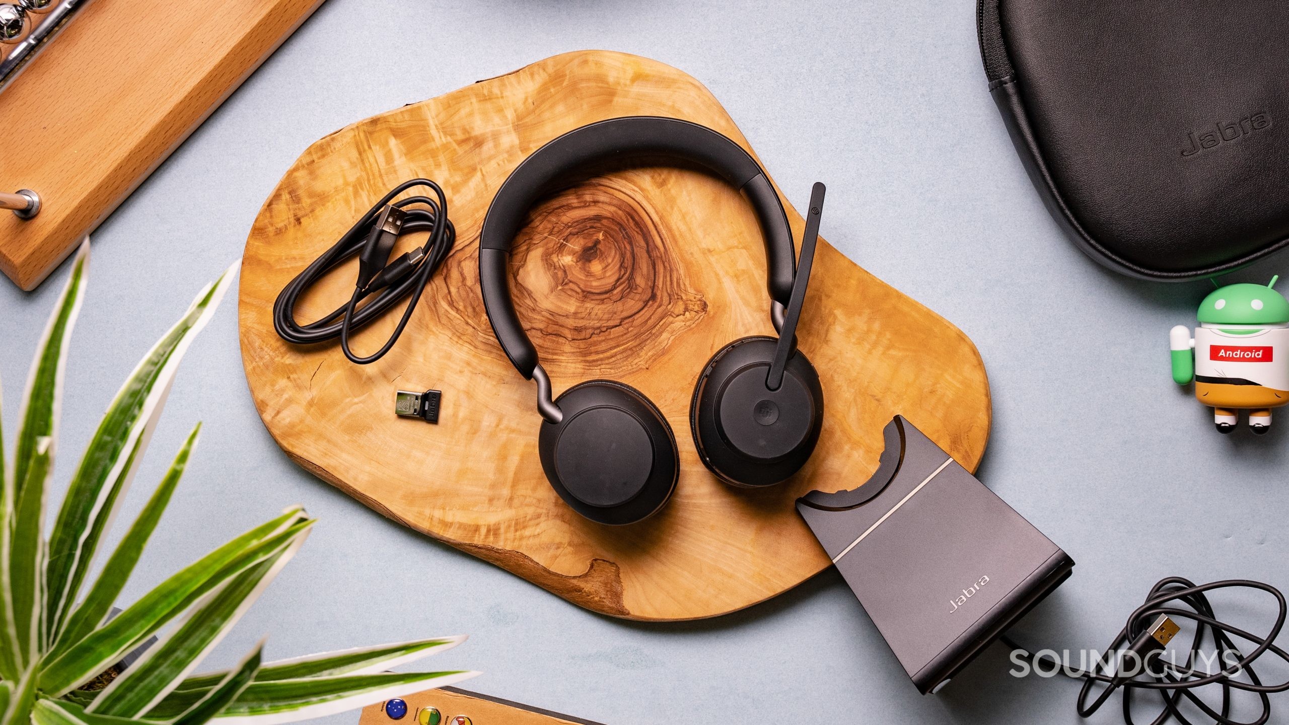 The Jabra Evolve2 65 sitting on a table with its accessories spread around it.