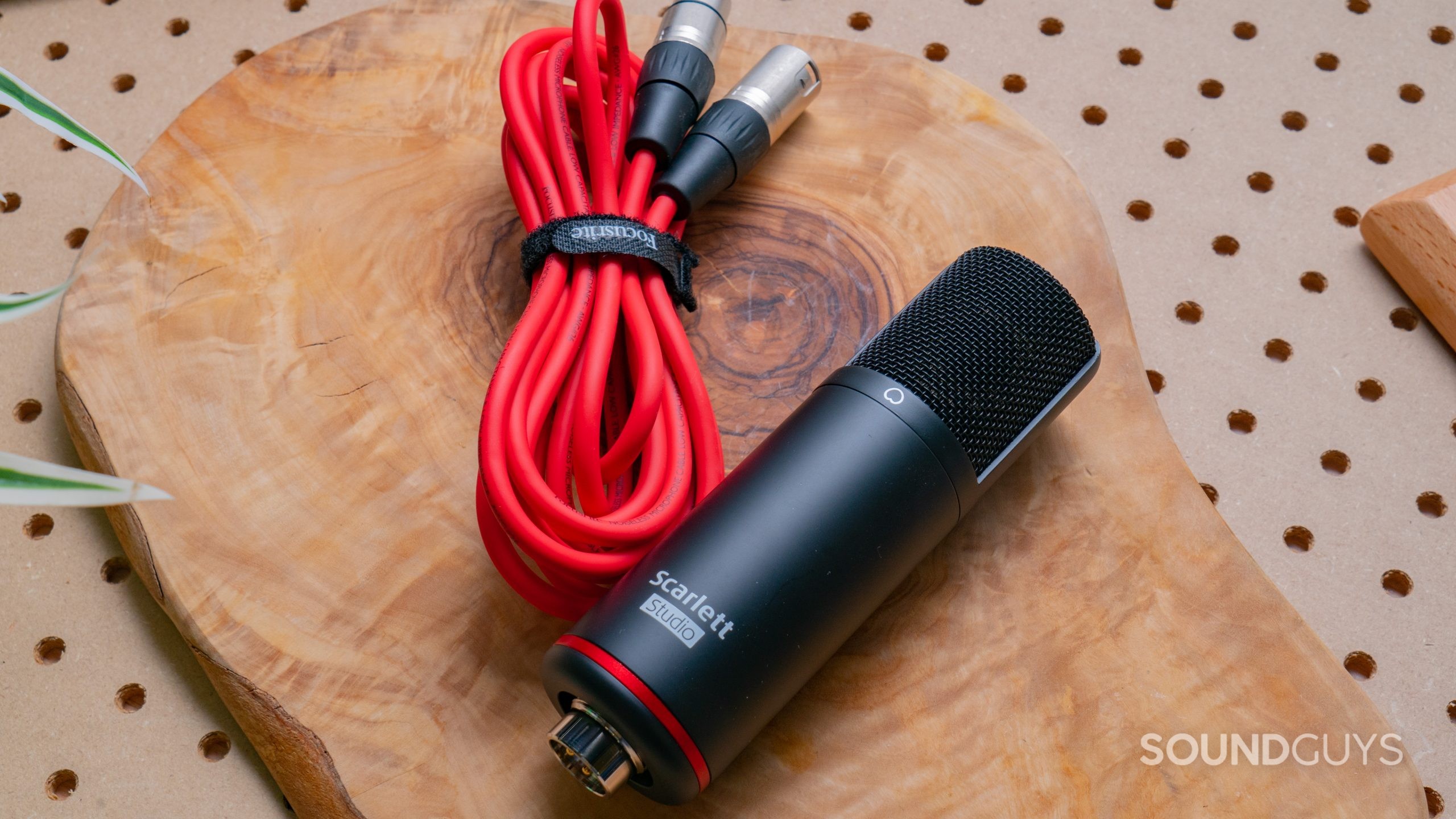 A bright red XLR cable is on a wood surface next to the Focusrite Scarlett condenser mic.