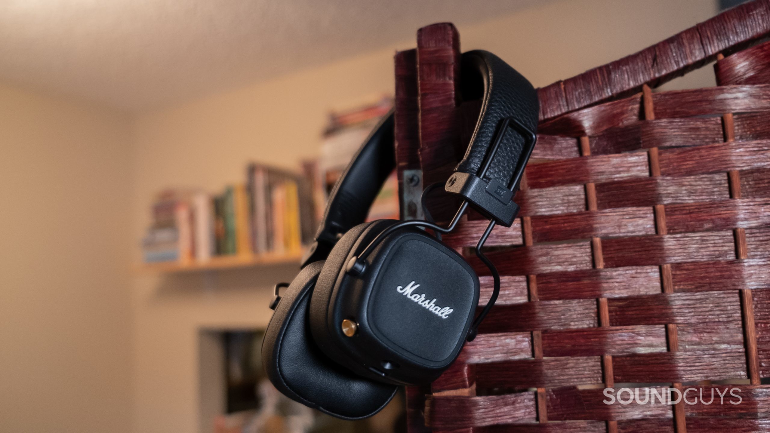 The Marshall Major IV slung over a rattan screen with blurred books in the background.