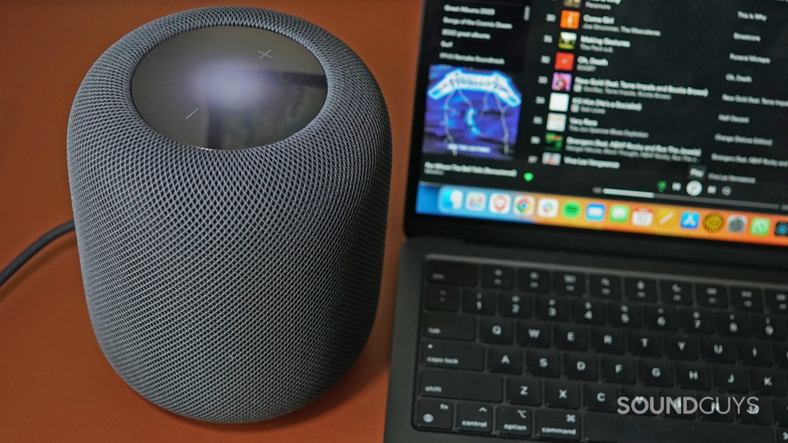 The Apple HomePod (2nd Generation) Sits on a leather surface next to an Apple MacBook Air.