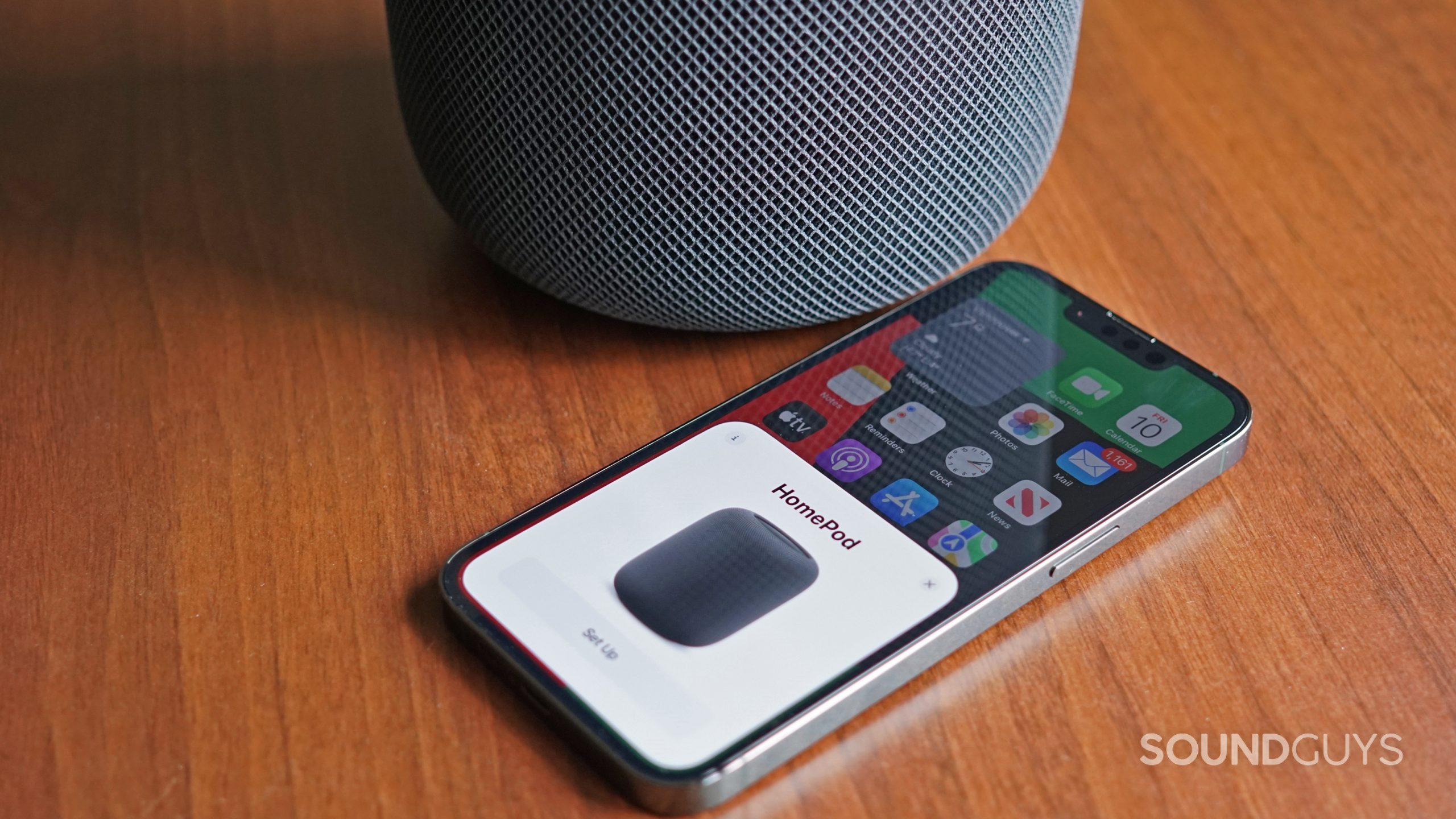 An Apple iPhone 13 Pro displays the initial setup card of the Apple HomePod (2nd generation) next to the smart speaker.