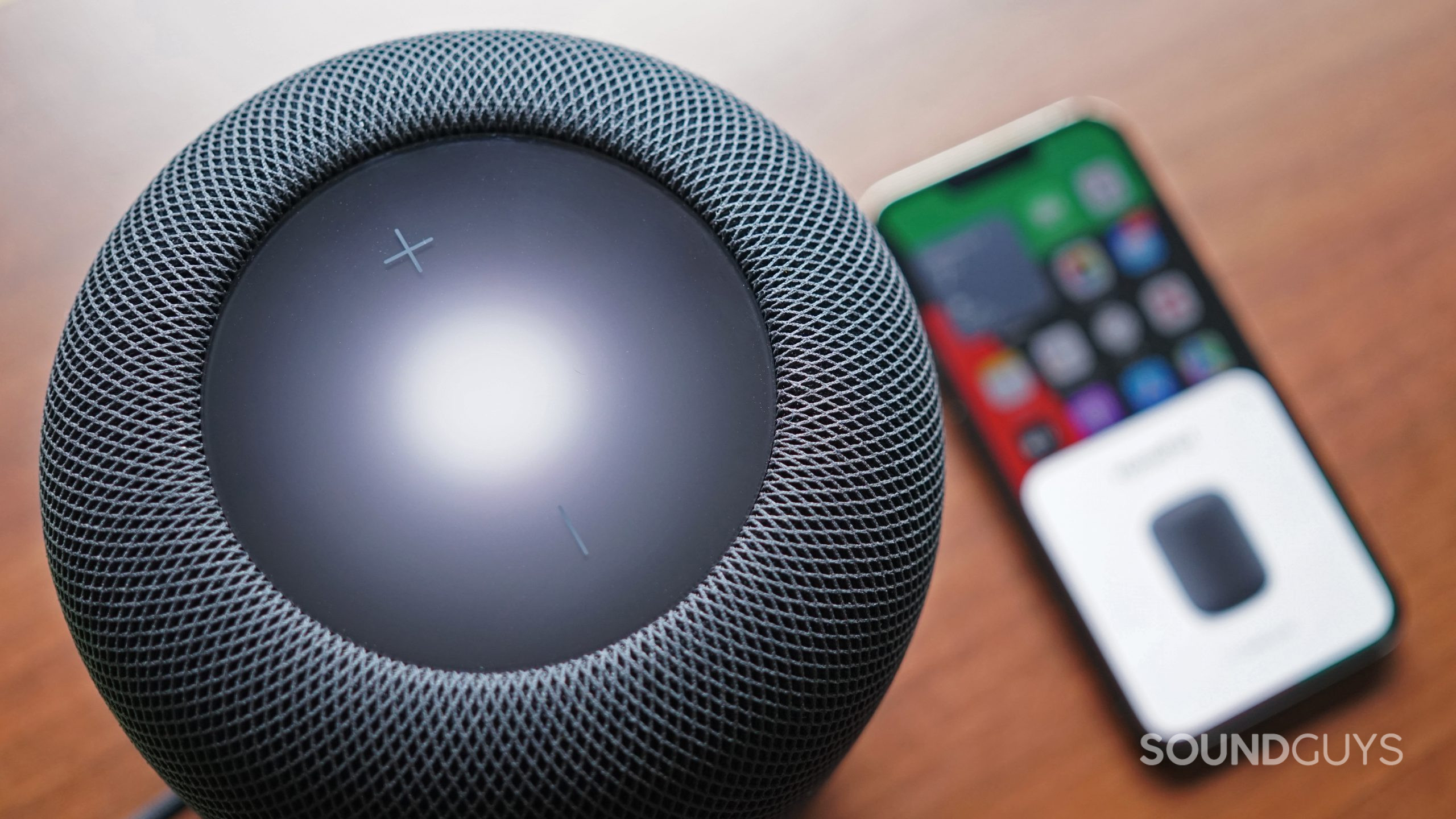 An aerial close up of the Apple HomePod (2nd Generation) with the Apple iPhone 13 Pro in the background.