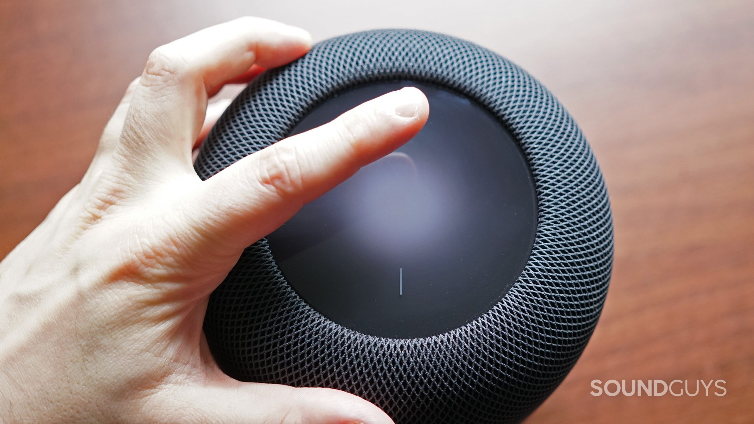 A hand rests above the Apple HomePod (2nd Generation) touch panel.