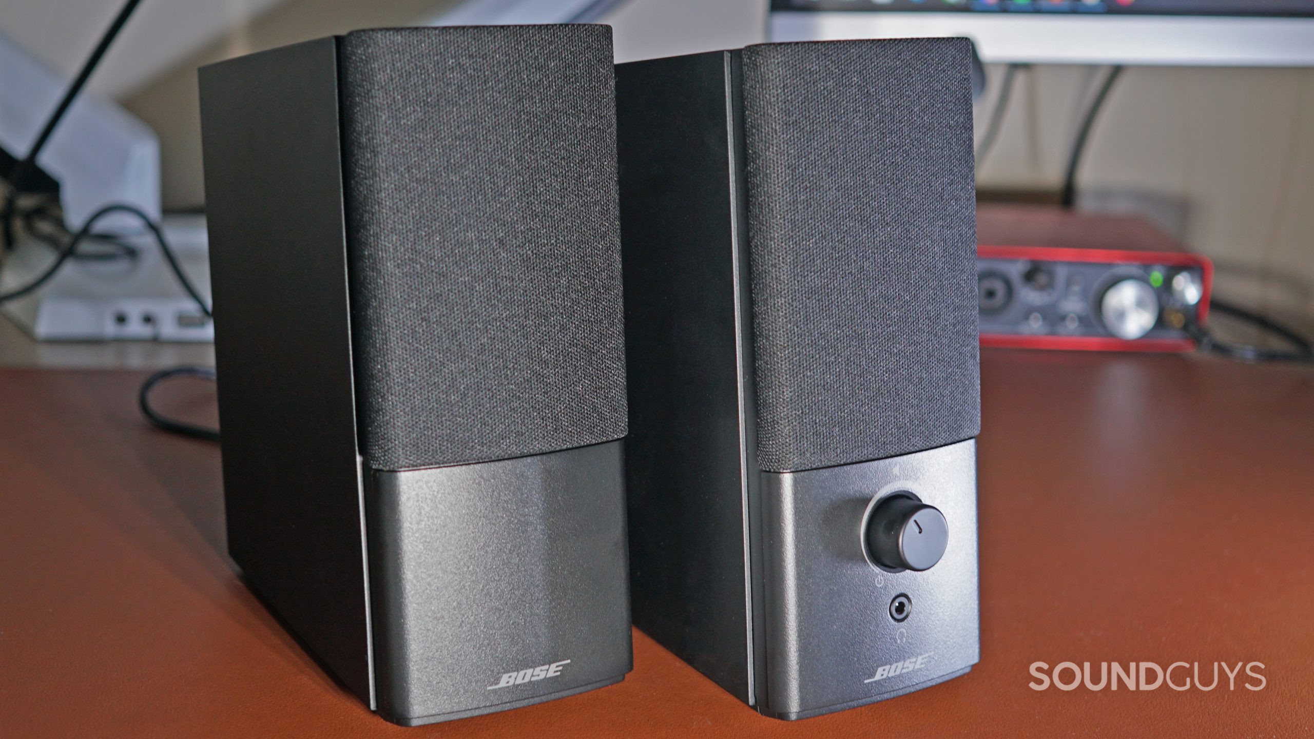 The Bose Companion 2 Series III speakers stand on a leather surface in front of ViewSonic monitors and a Focusrite Scarlett 2i2 audio interface.