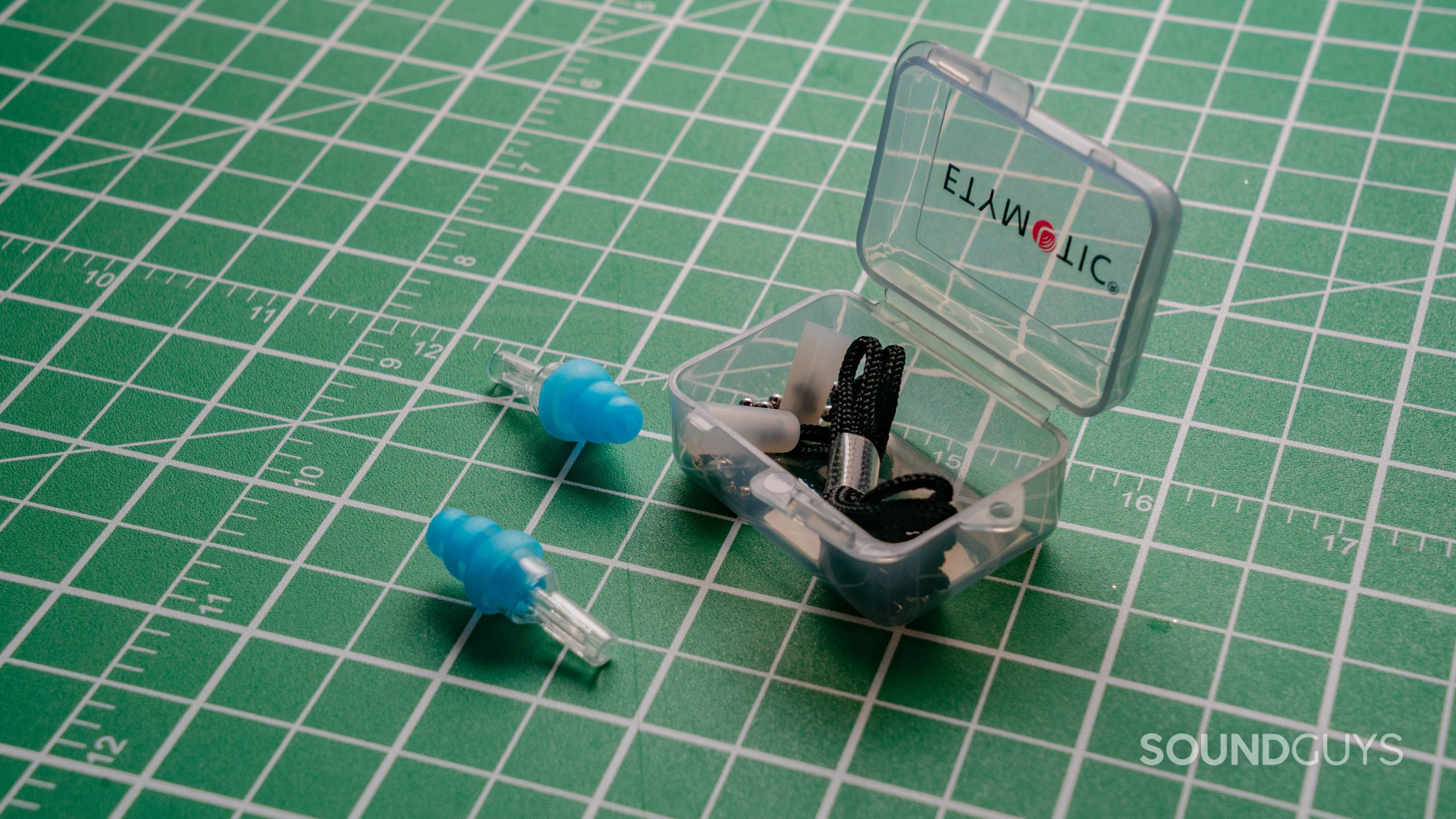 Etymotic earplugs with case against a white on green grid.