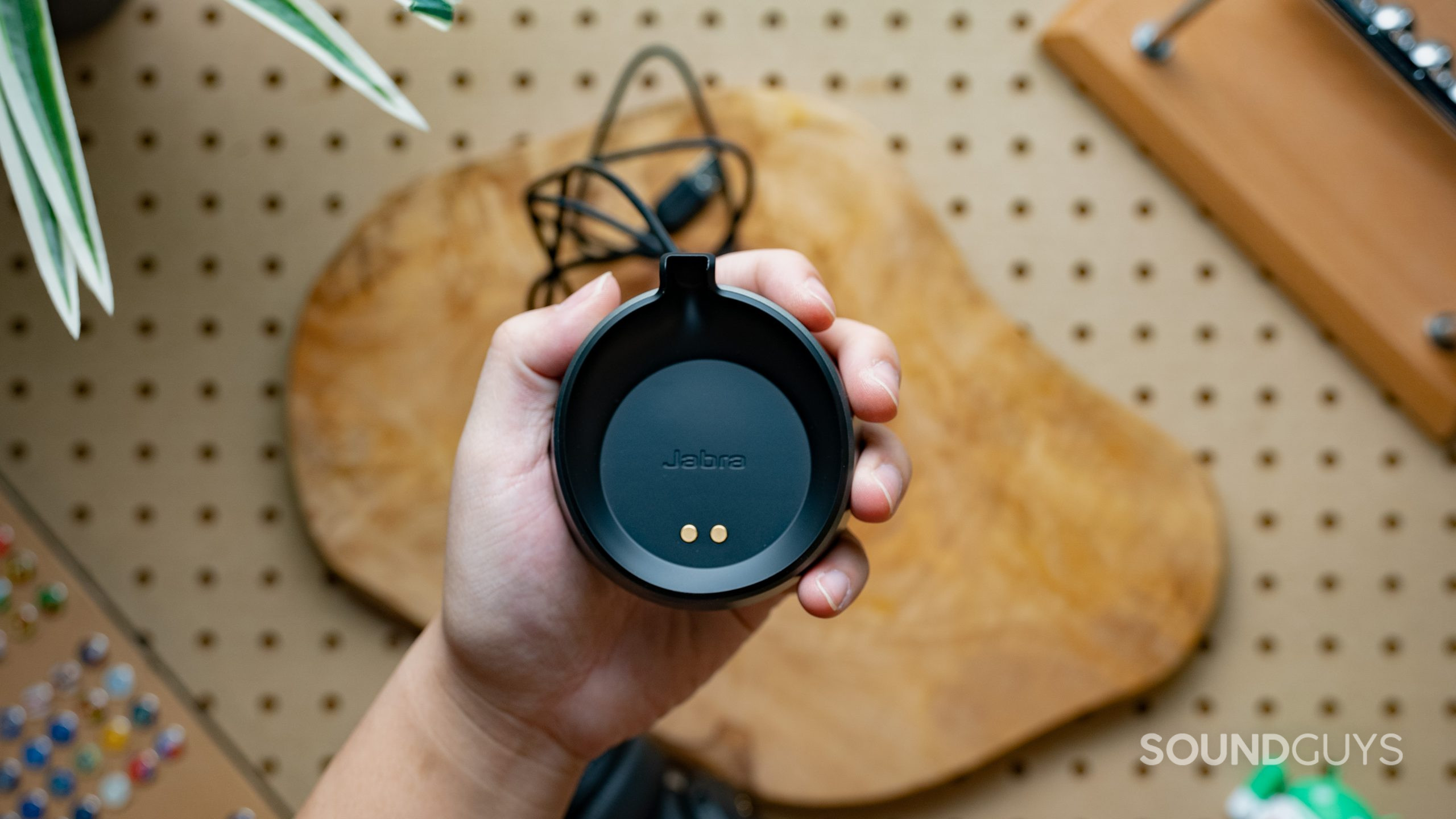 The charging cradle of the Jabra Evolve2 75 being held in someone's hand showing the two metal contacts.