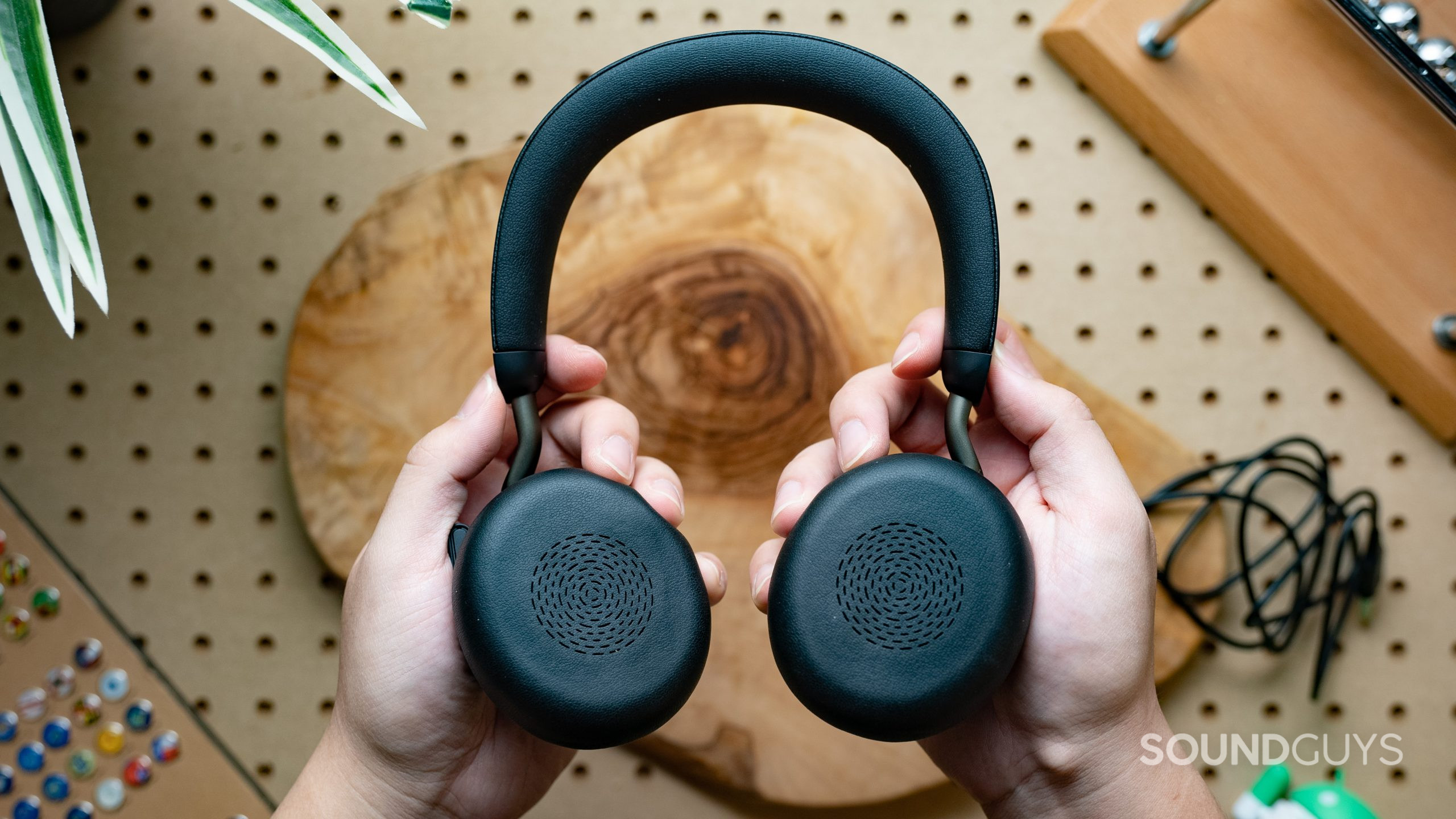The Jabra Evolve2 75 headset being held firmly with two hands, with the pads of the earcups facing the viewer.