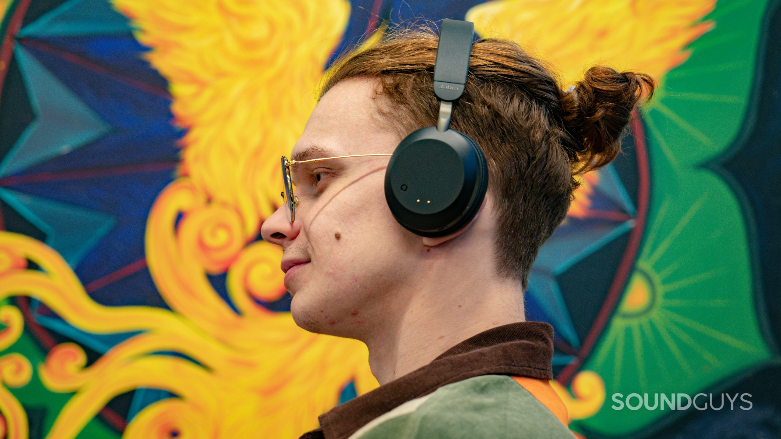 The Jabra Evolve2 75 being worn on an individual's head against a colourful background.