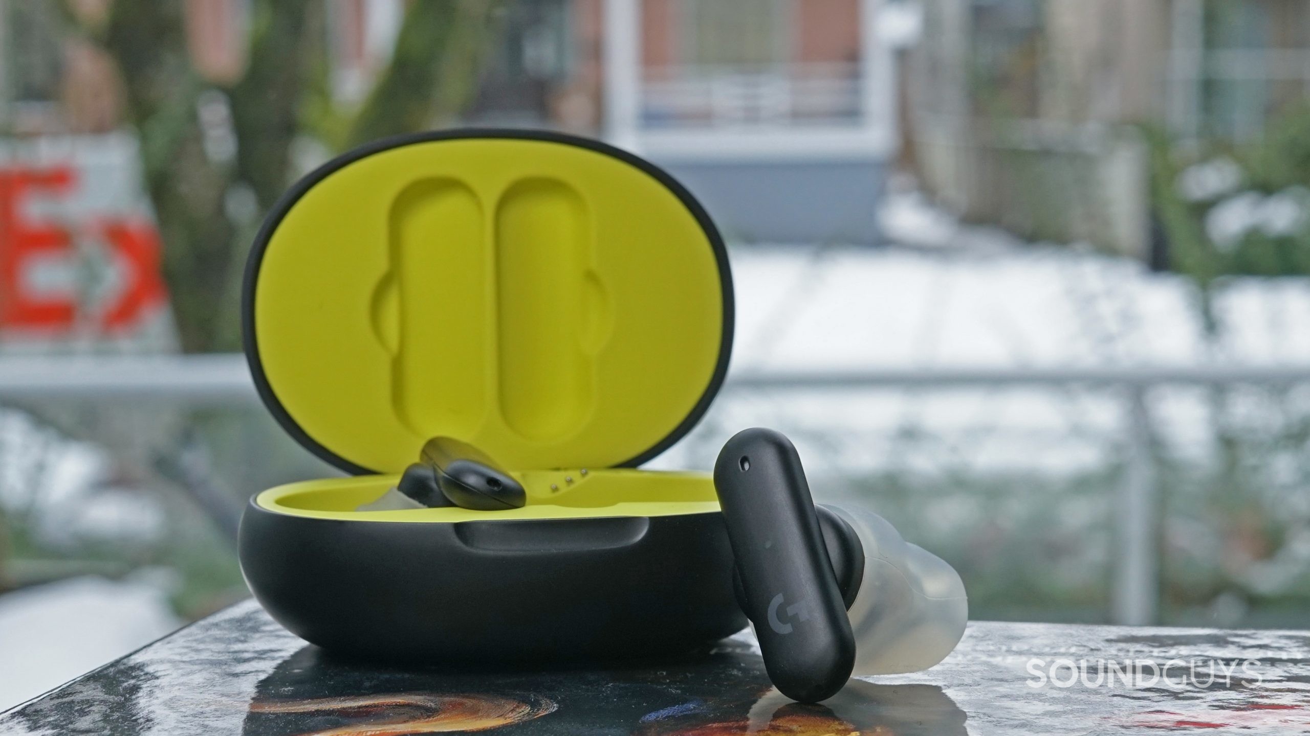 Logitech G Fits earbuds with open case sitting on an outdoor table