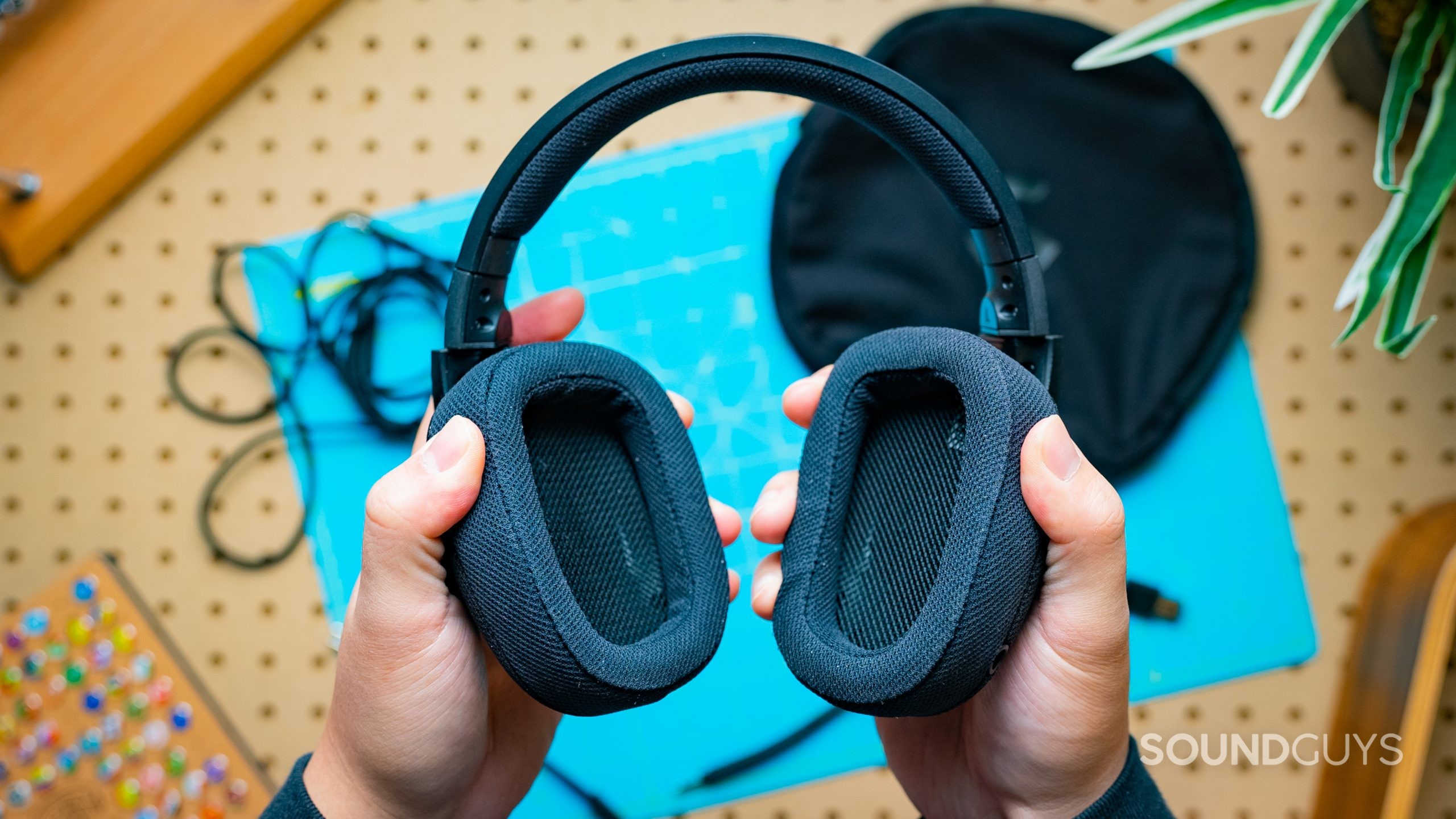 The Logitech G433 being held in two hands with a blue surface behind it.