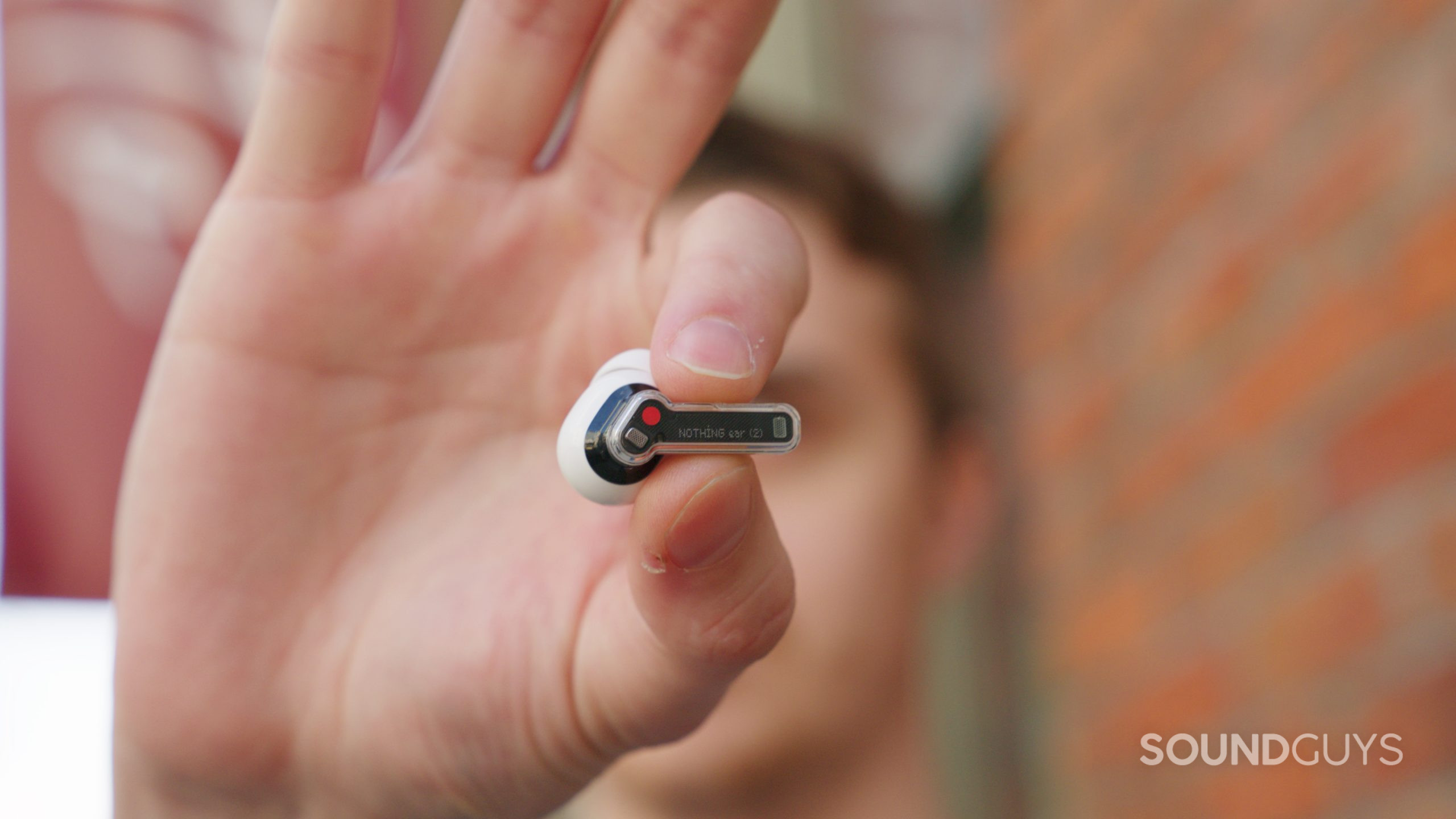 A hand squeezes the pressure sensitive stem on the Nothing Ear (2).