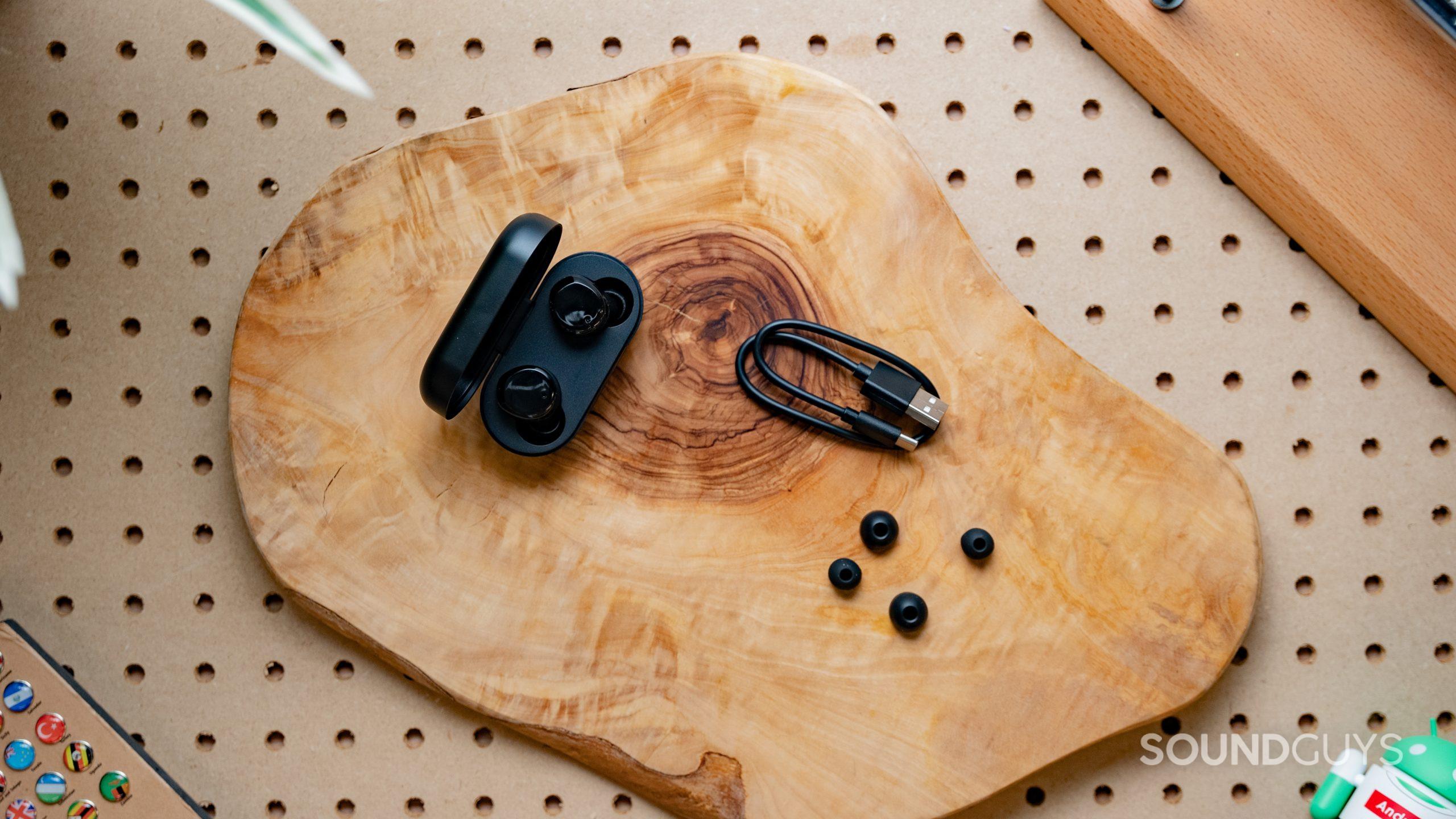 TOZO T12 earbuds on table next to extra ear tips and the USB C charging cable