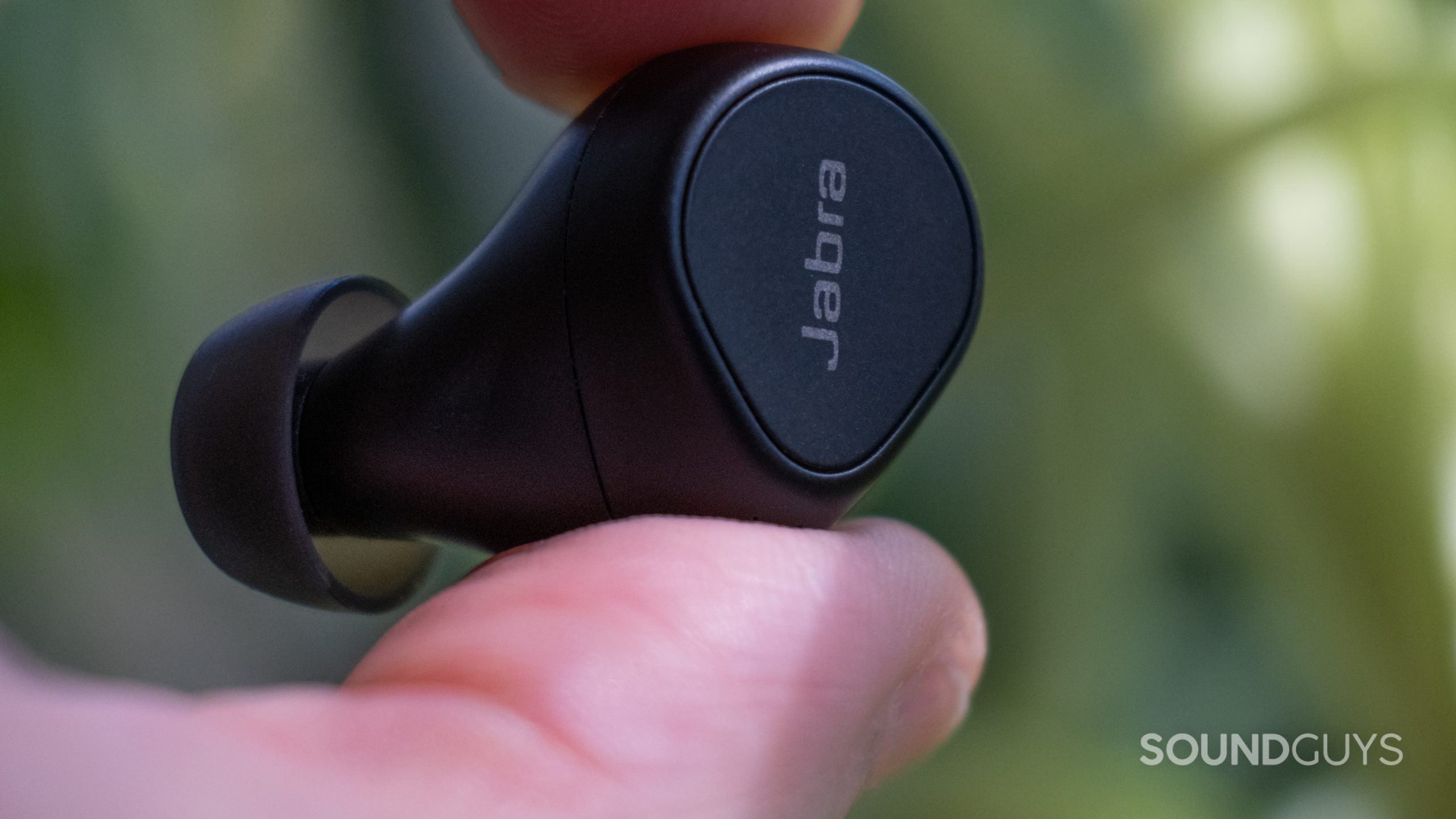 A thumb and index finger hold a Jabra Evolve2 Bud in a close up.