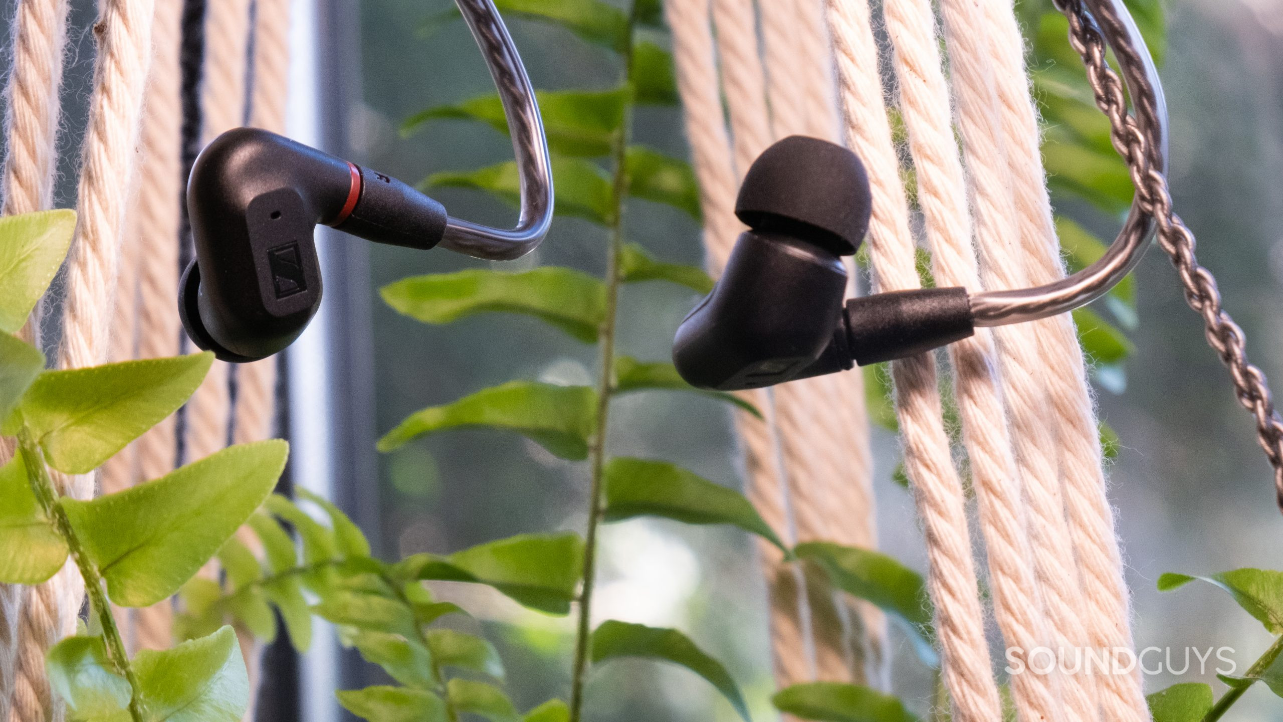 A close up of the Sennheiser IE 200 hangs from some twine with a plant.