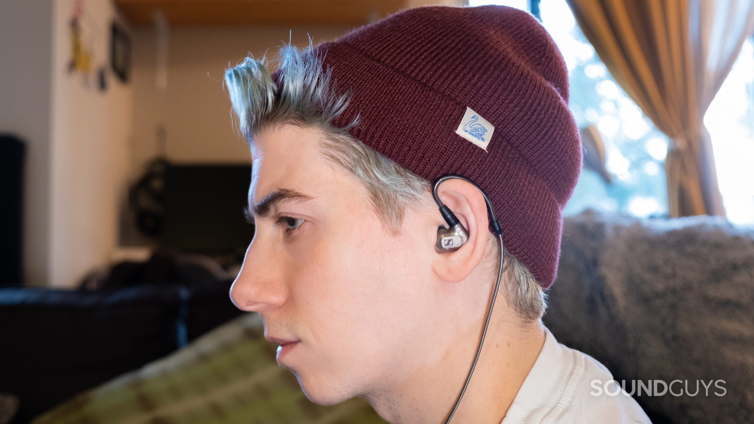A man faces left with a beanie on wearing the Sennheiser IE 600 with the cable wrapping over his ear.