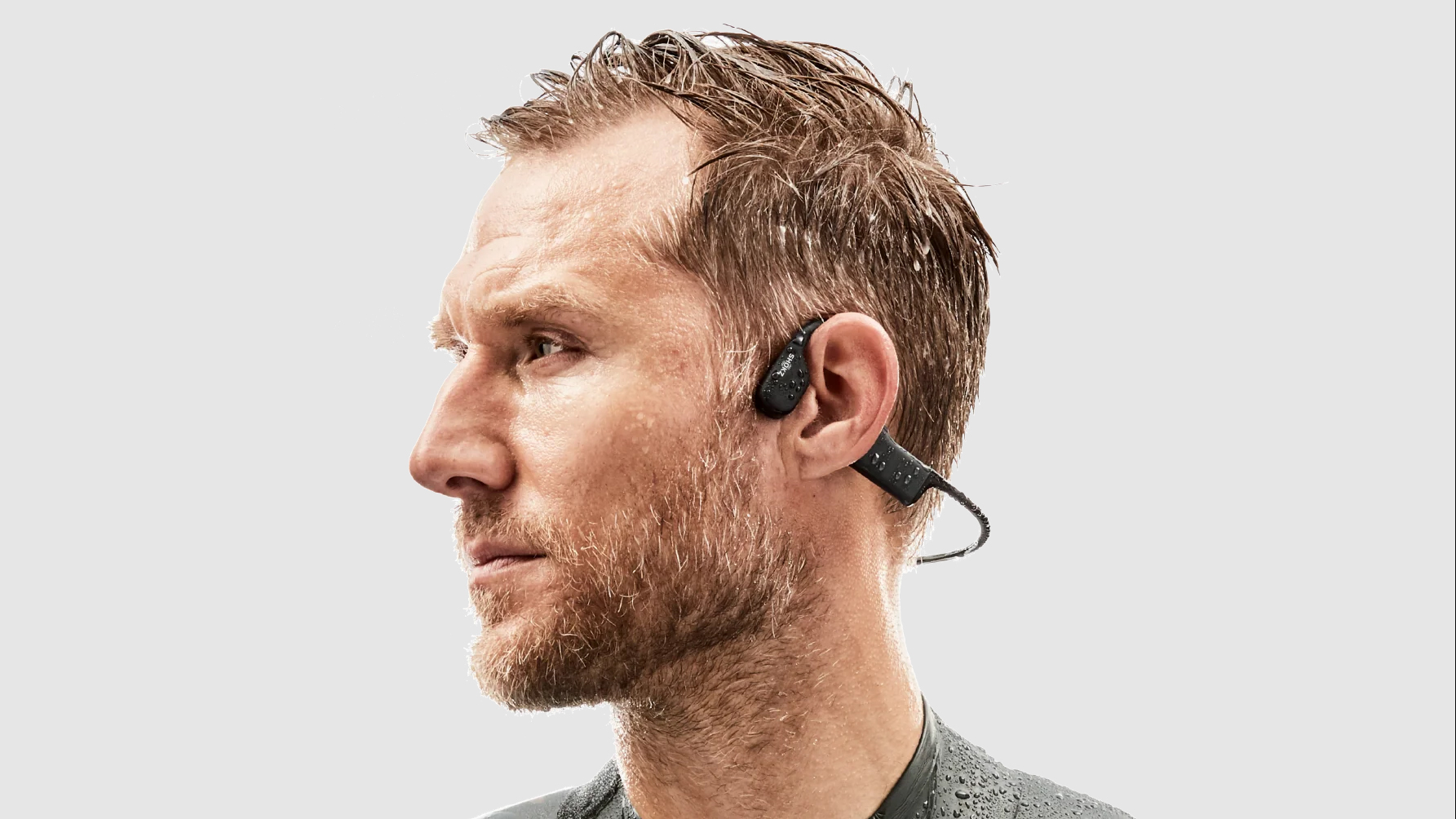 A man wearing Shokz OpenSwim MP3 Bone Conduction Swimming Headphones