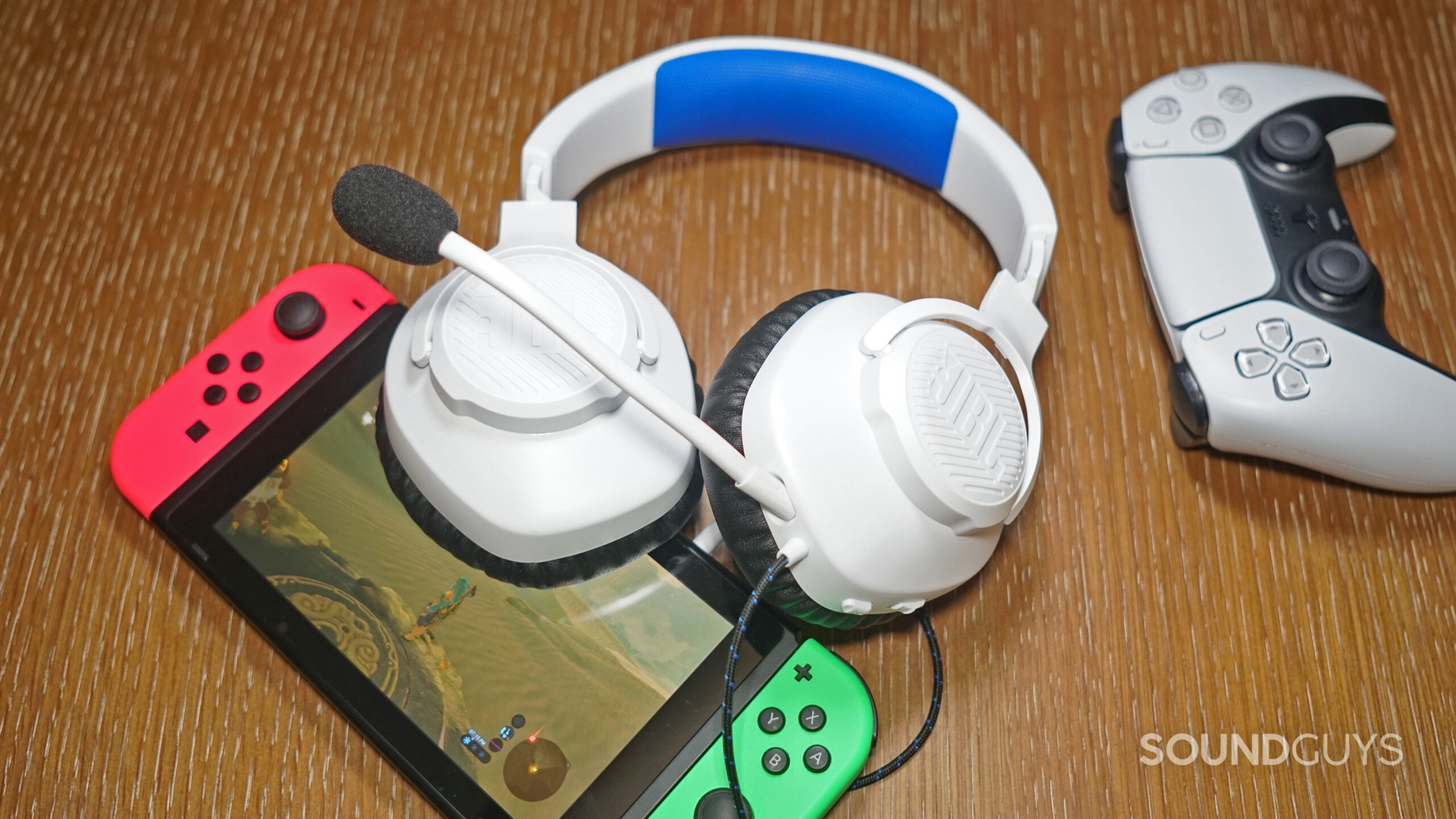 The JBL Quantum 100P lays on a Nintendo Switch running Legend of Zelda Breath of the Wild, next a PlayStation dualsense controller.