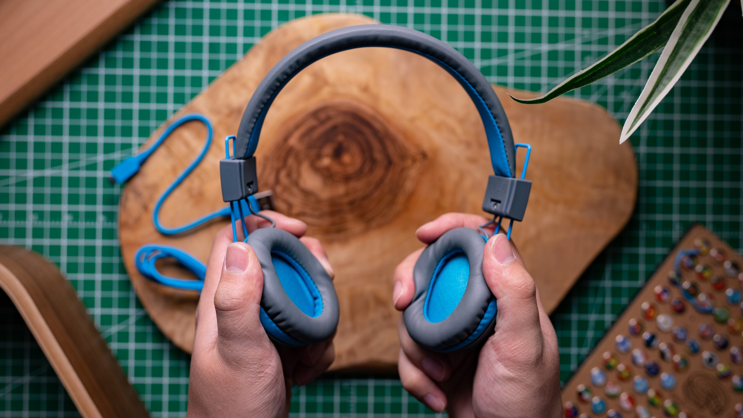 A photo of a man holding the JLab JBUDDIES STUDIO WIRELESS over wood and grid.