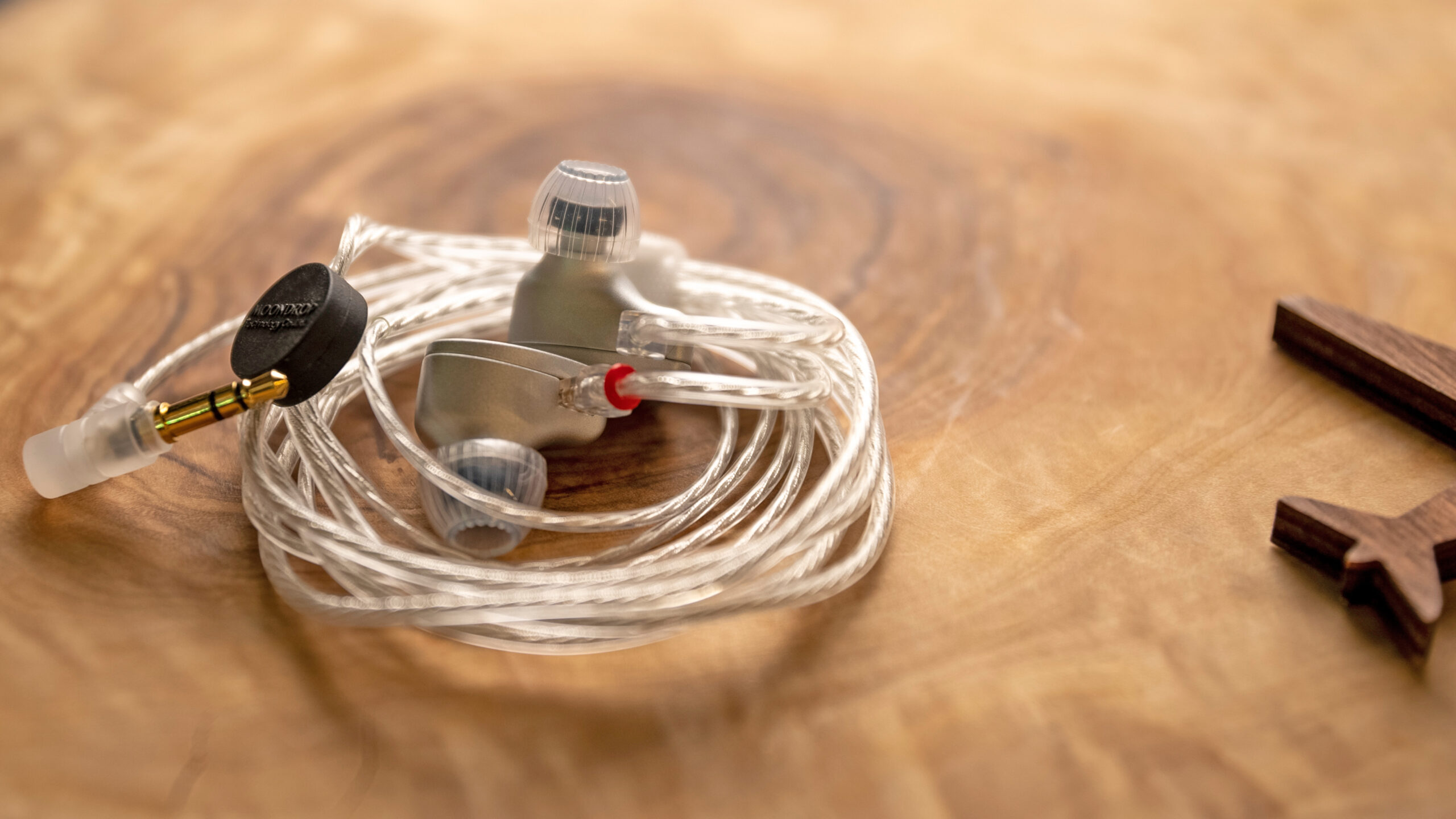 A closeup of the Moondrop Aria SE coiled up together on top of a wooden table.