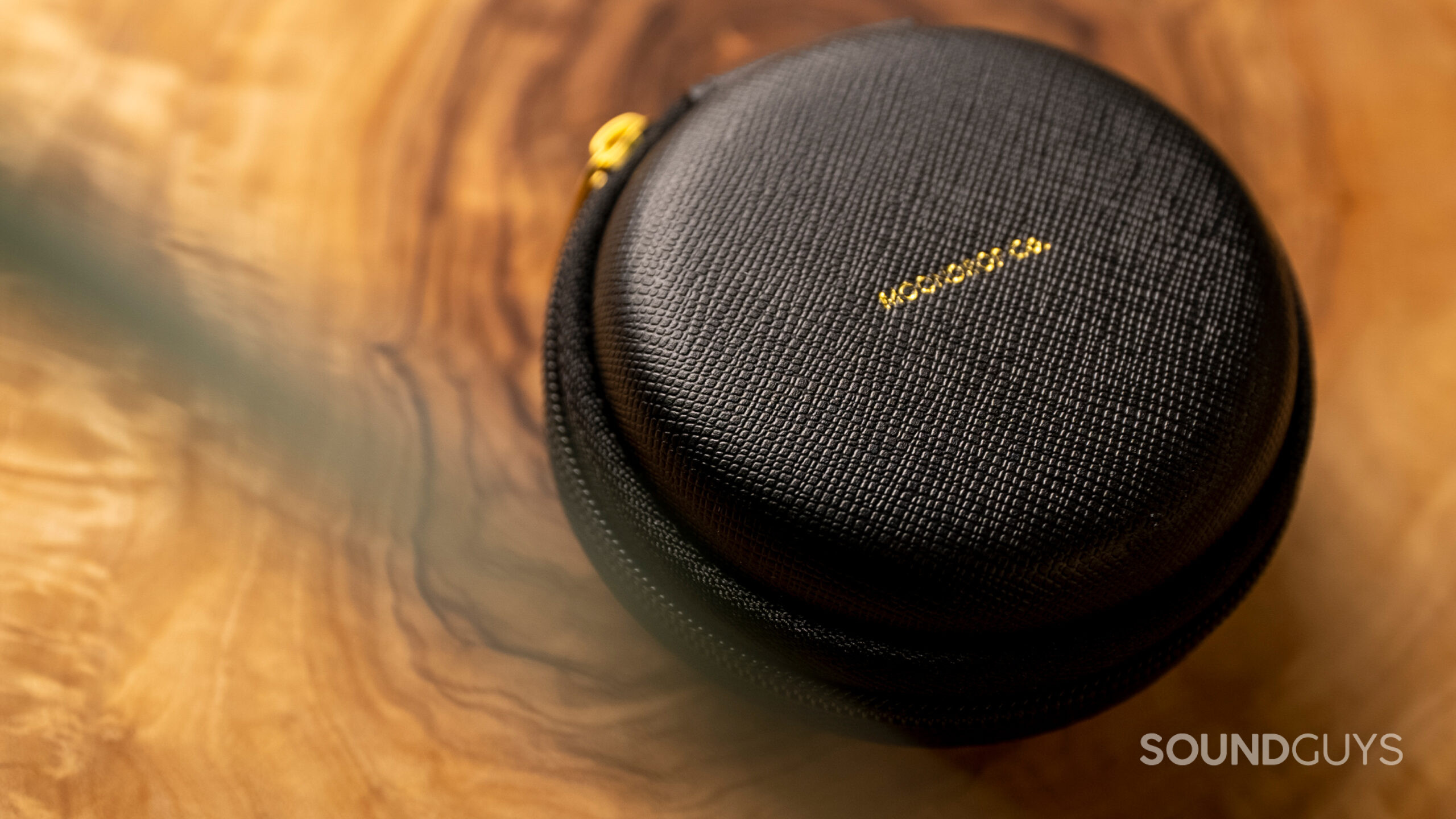 The Moondrop Aria zip case rests on a wood surface.