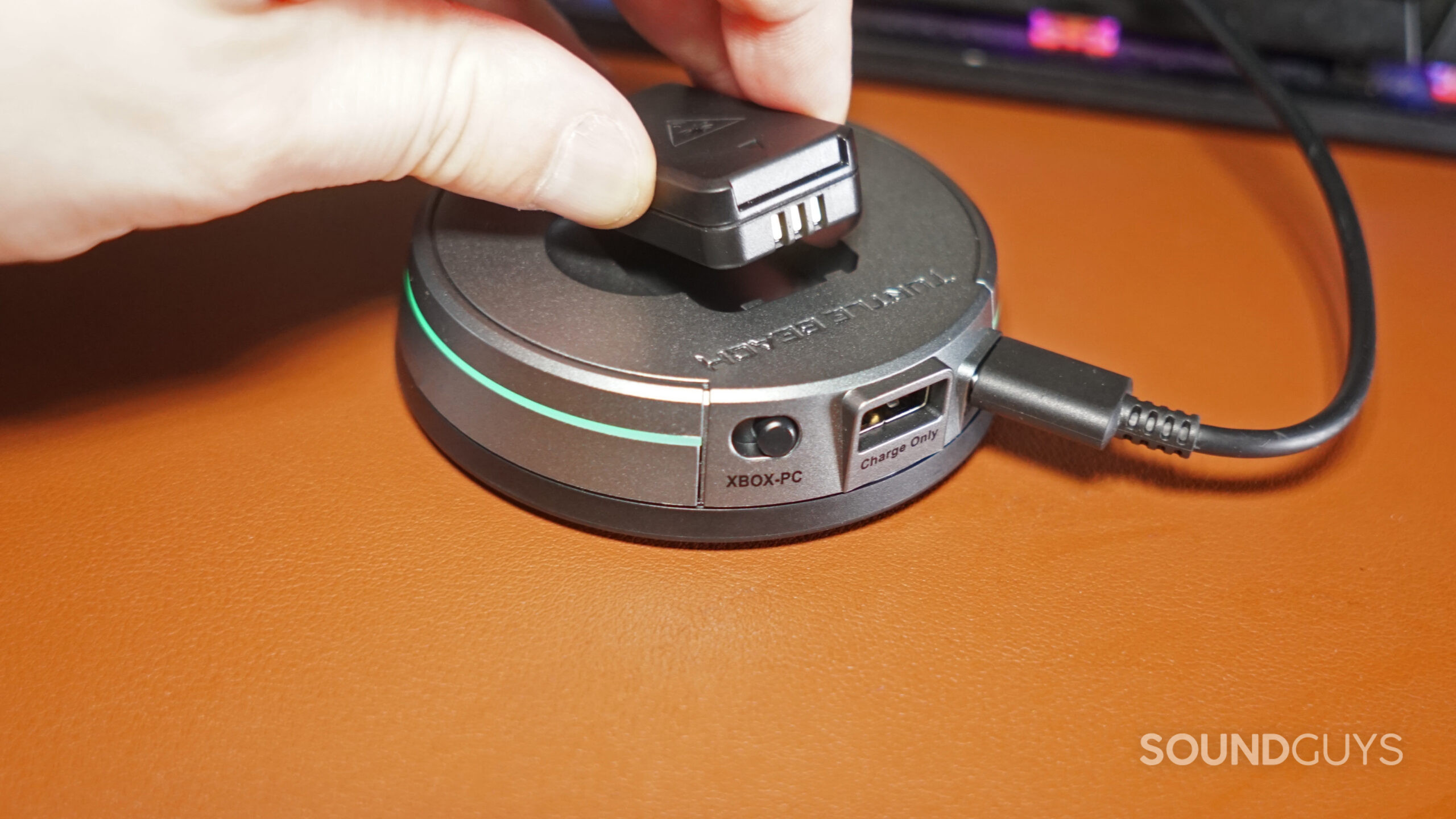 A close up shot of a hand putting the extra battery of the Turtle Beach Stealth Pro into its charging cradle.