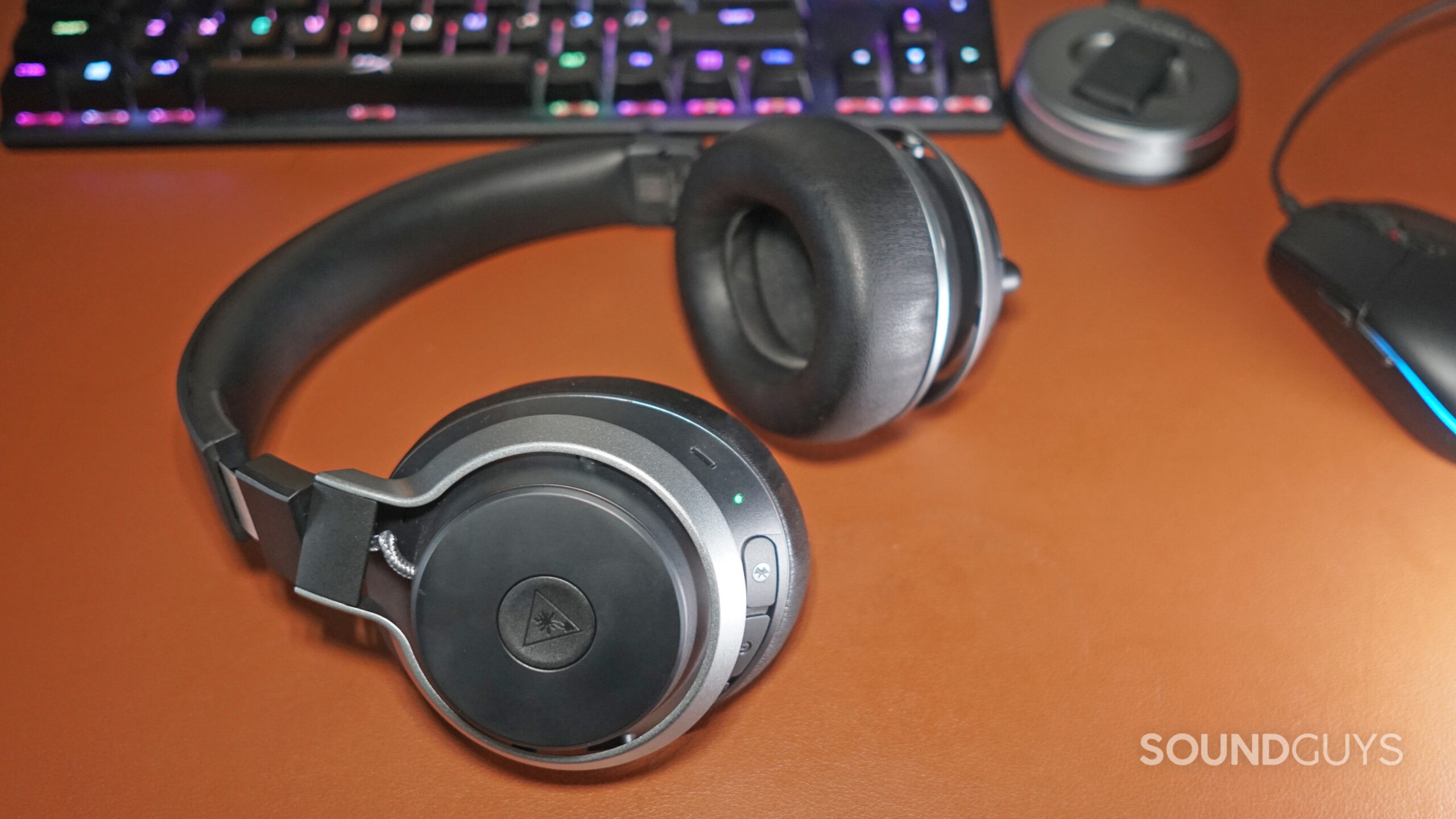 The Turtle Beach Stealth Pro lays on a leather desktop, in front of a HyperX mechanical gaming keyboard and a Logitech gaming mouse.