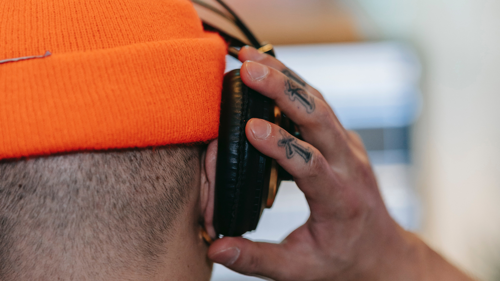 A man fits headphones with his ear sticking out of the ear cup.