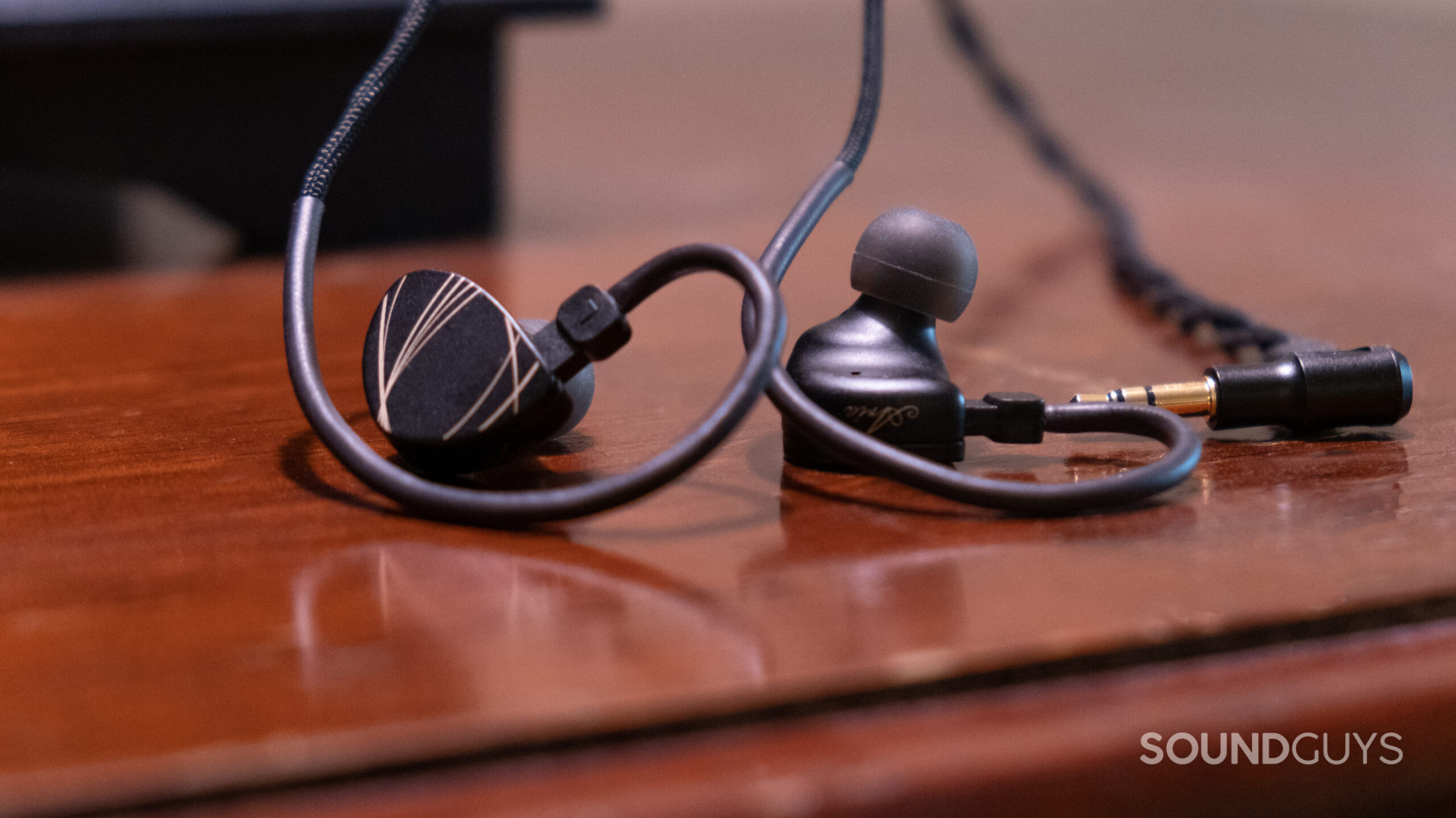 The Moondrop Aria earbuds shown close up on a dark wood surface.