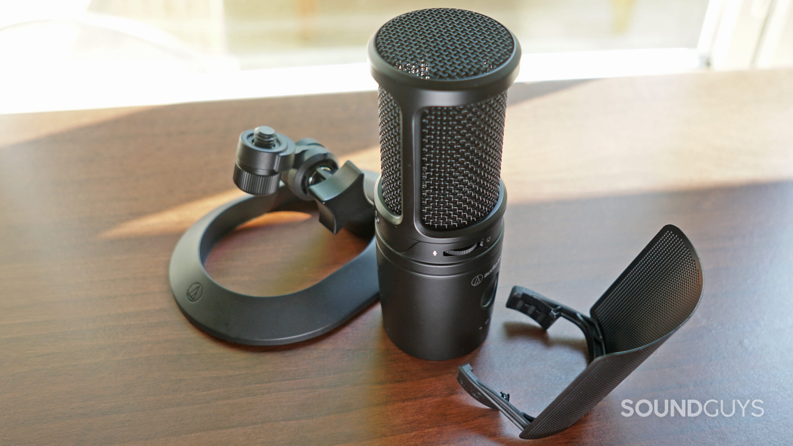 The AT2020USB-XP microphone surrounded by the two included accessories, the mount and the pop filter.