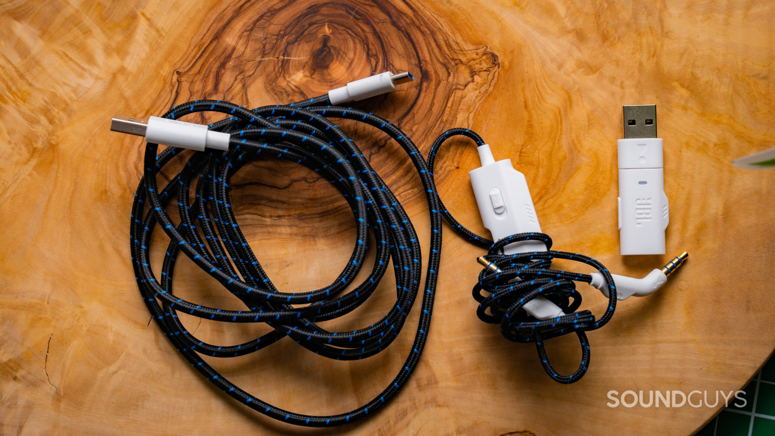 JBL Quantum 910P Dongle Image #1 The JBL Quantum 910P cable sitting on top of a wooden tabletop.