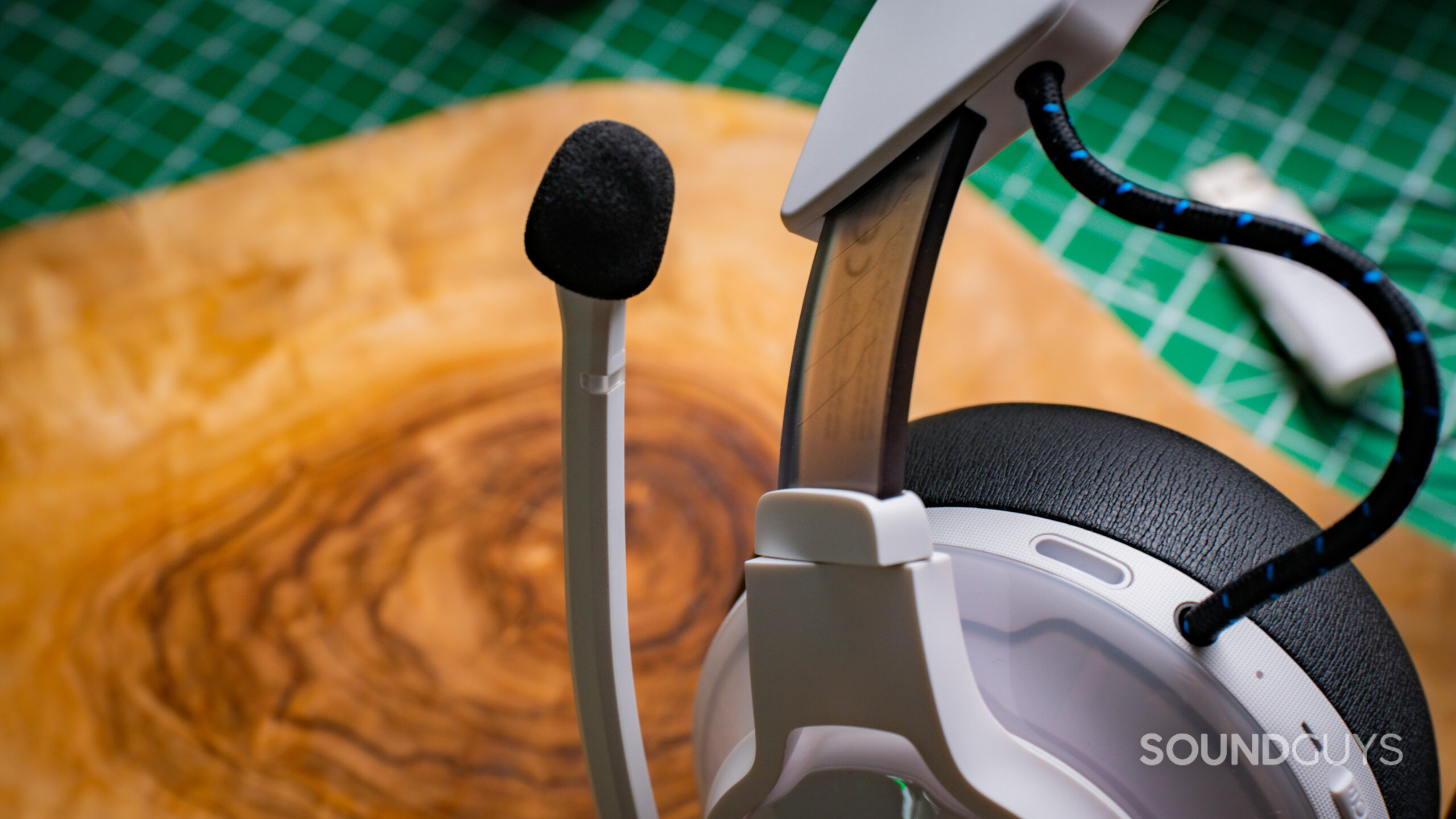 JBL Quantum 910P Headband Image #2 A closeup of the JBL Quantum 910P microphone against a wooden tabletop.