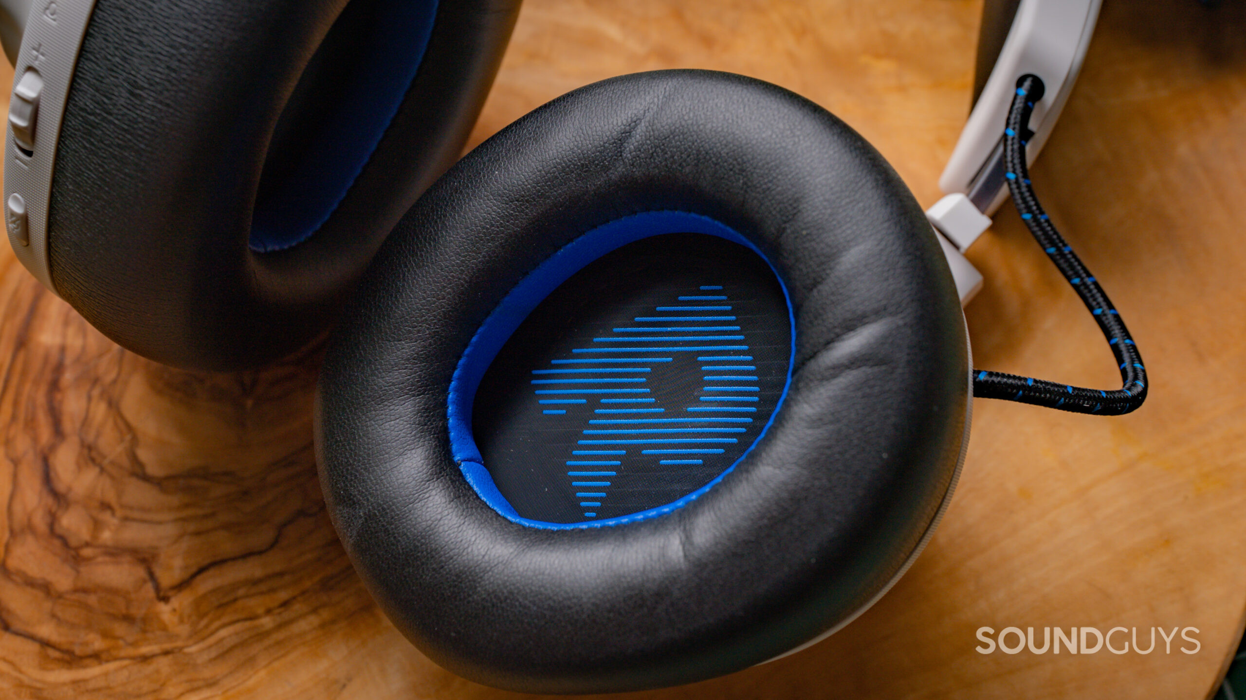 A closeup of the right earcup of the JBL Quantum 910P, with a clearly visible blue letter R.
