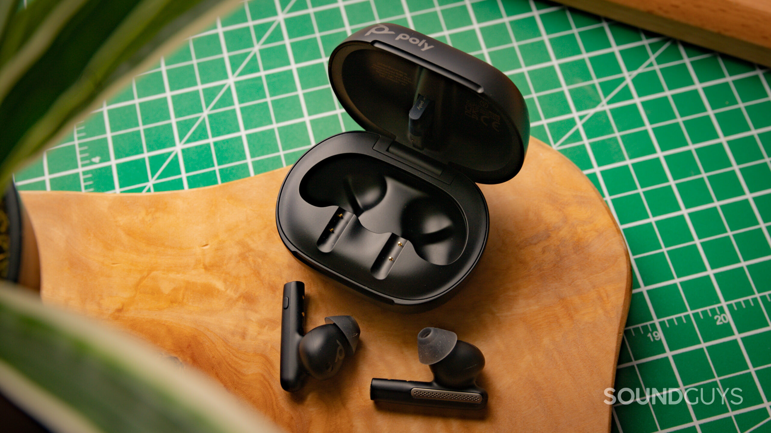 Poly Voyager Free 60+ UC with earbuds laying outside of the open case.